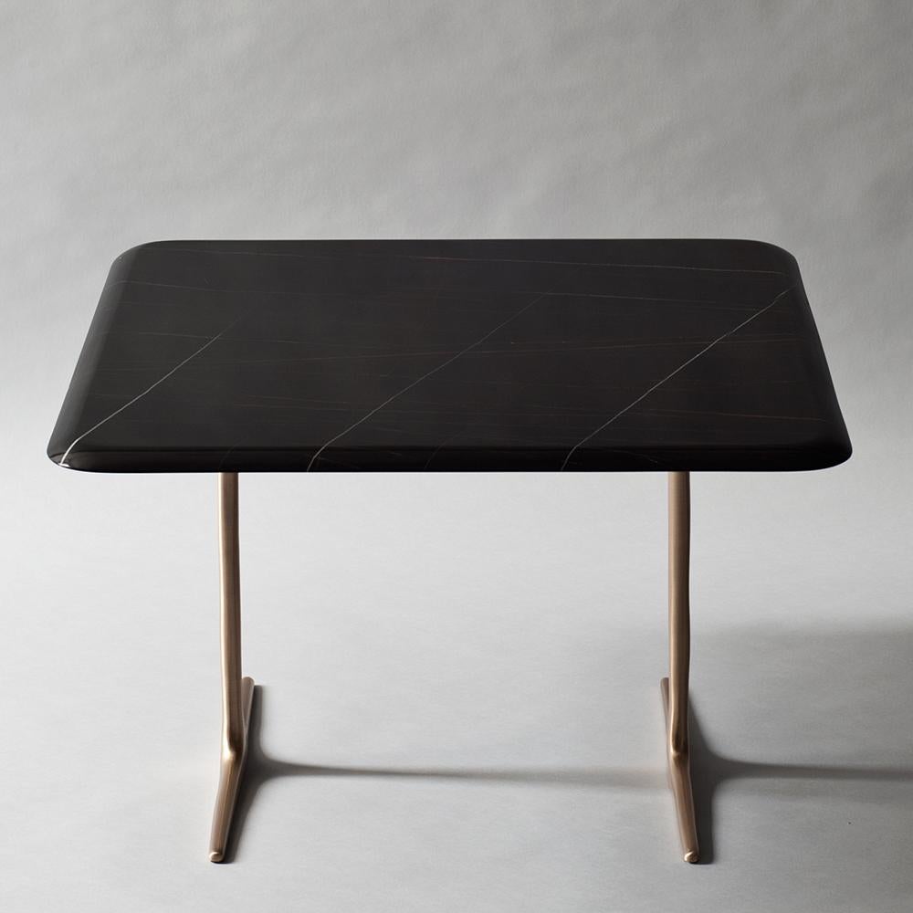 The Lark side or cocktail table by DeMuro Das has a slender top made of Nero Saint Laurent marble with a delicately tapered edge. Hand-cast solid satin bronze legs support the top. These pieces can be used singly or paired and used as a coffee or