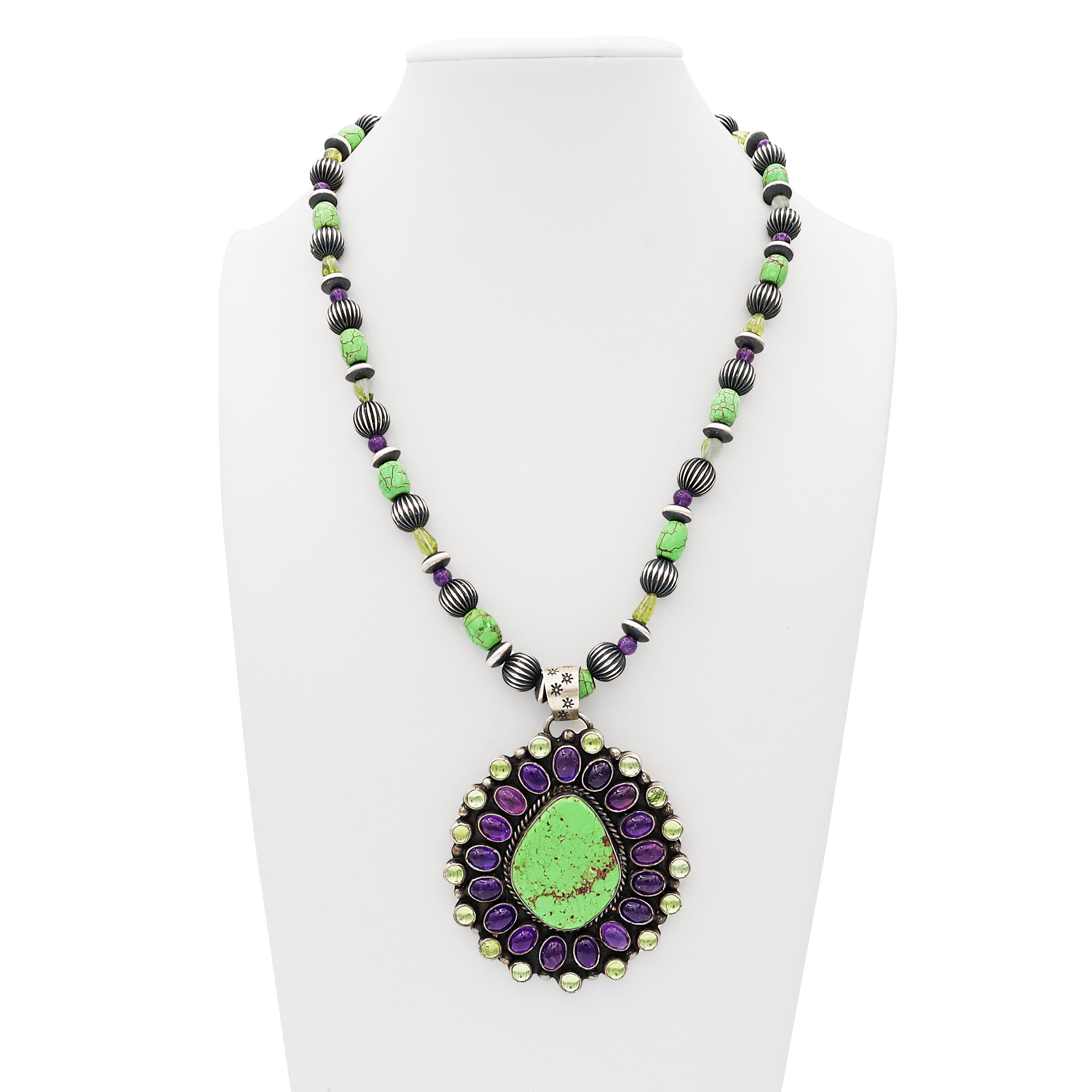This stunning handcrafted necklace by LaRose Ganadonegro, a talented Navajo artisan, is a vibrant celebration of Southwestern style and Native American craftsmanship. Made from sterling silver, the piece features a bold design anchored by a striking
