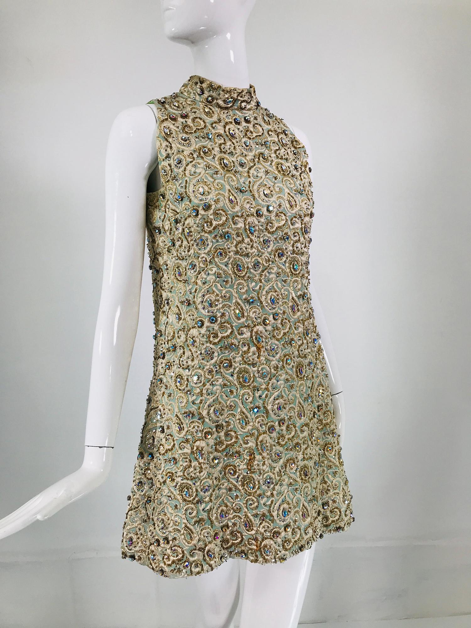 Marie McCarthy for Larry Aldrich heavily beaded brocade, A line halter neck mini dress from the 1960s. Aqua, cream and gold metallic brocade is covered in large and small iridescent prong set rhinestones, sequins and beads. The dress has a mock neck