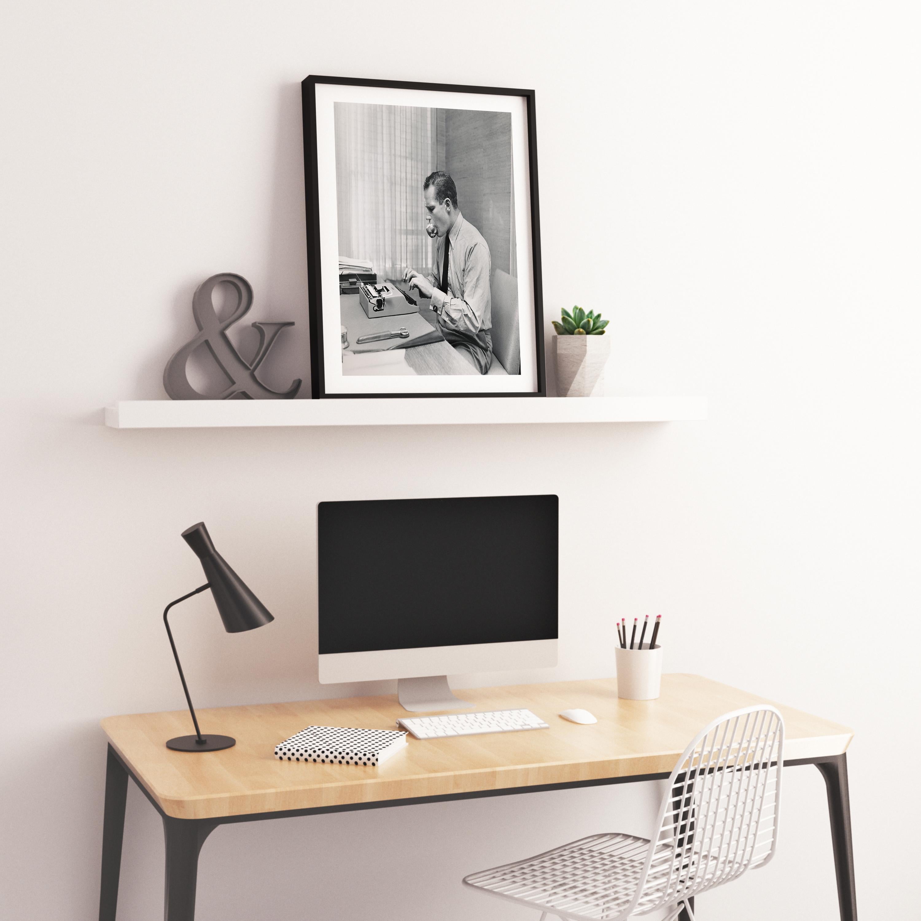 This black and white action shot features actor Charlton Heston working at his desk, typing while comedically holding an apple in his mouth.

Charlton Heston was an American actor and political activist. As a Hollywood star, he appeared in almost