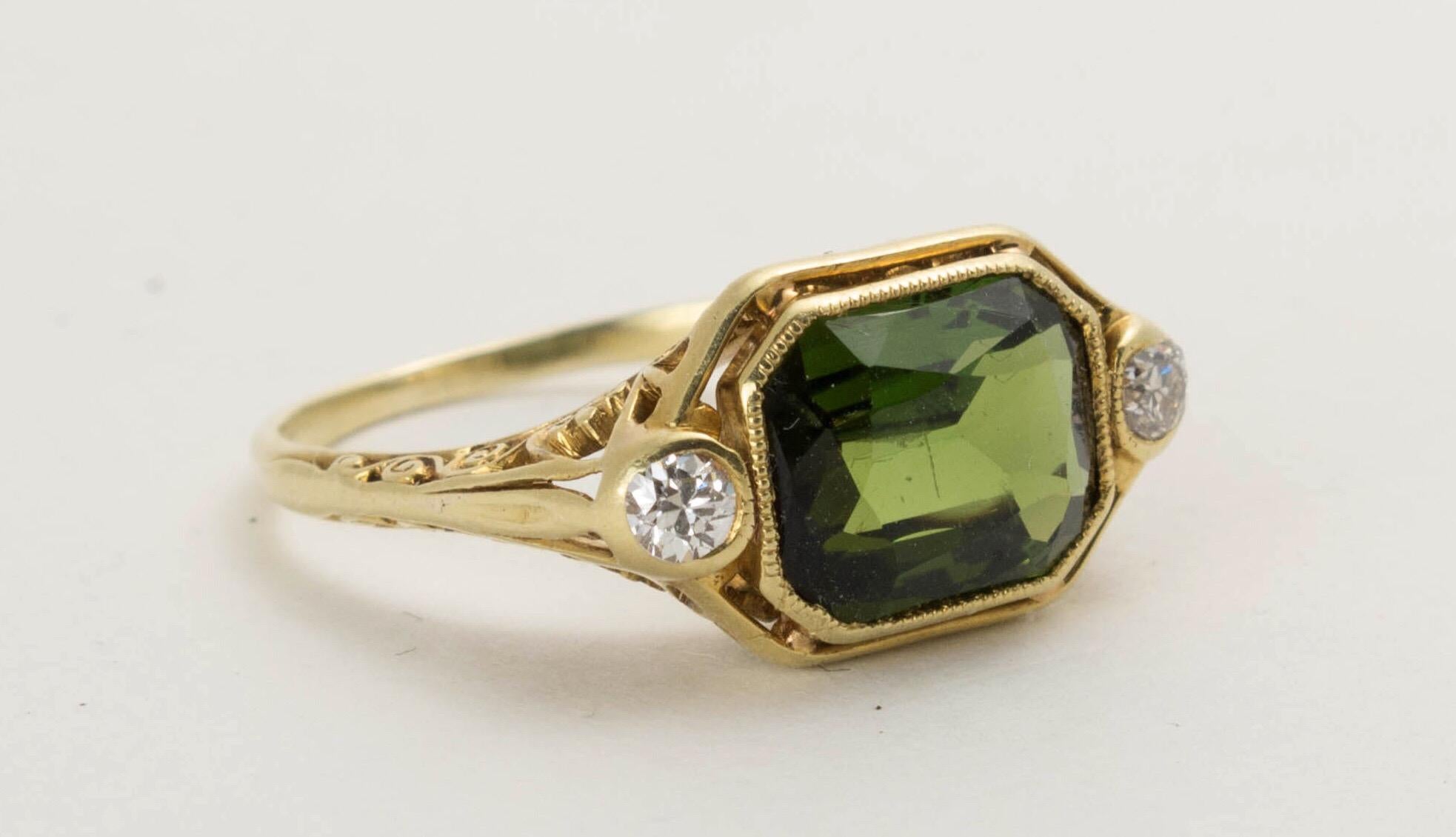 An antique art deco era Larter & Son 18 k yellow gold filigree ring with diamonds flanked on each side of a beautiful emerald cut green tourmaline.

Ring size: 6.5. Ring top is 9mm x 16mm.  Diamonds weight approx. 0.10 carats.  Maker's mark, 18k.