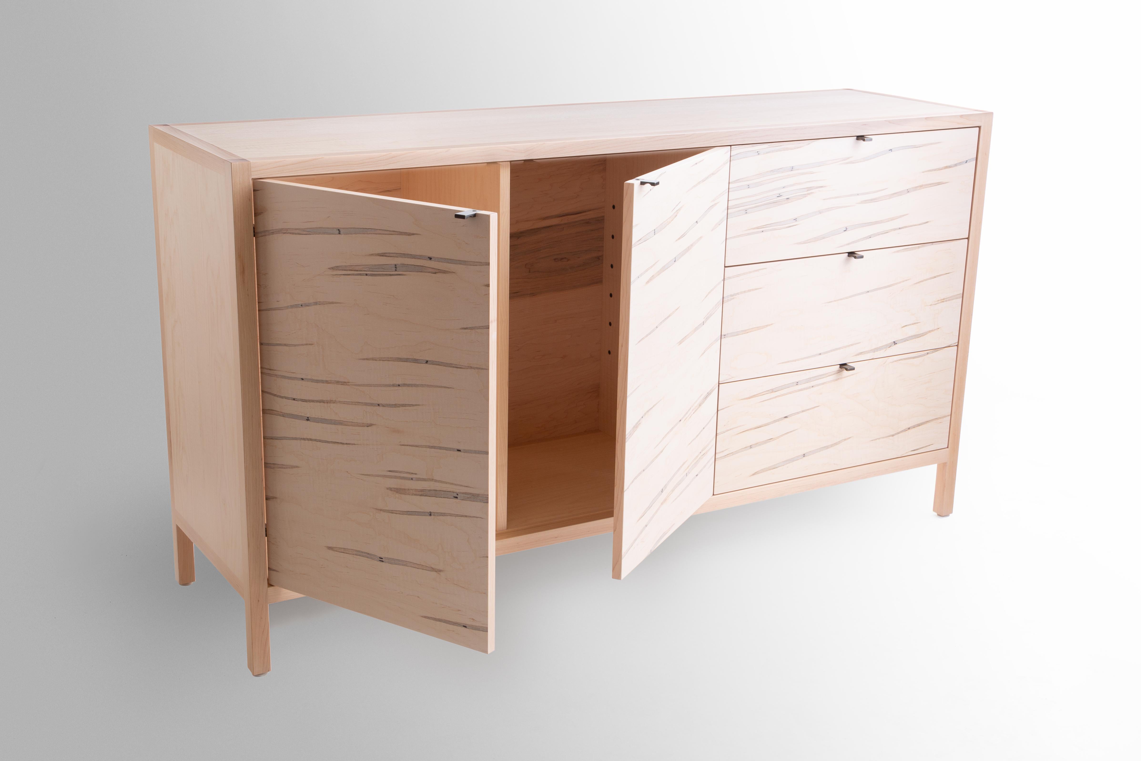 The Laska credenza is built in our Louisville, KY studio using premium hardwoods and thoughtfully selected wood veneers. This piece features custom veneered panels framed flush with solid hardwood edges and legs. The three solid wood drawers ride on