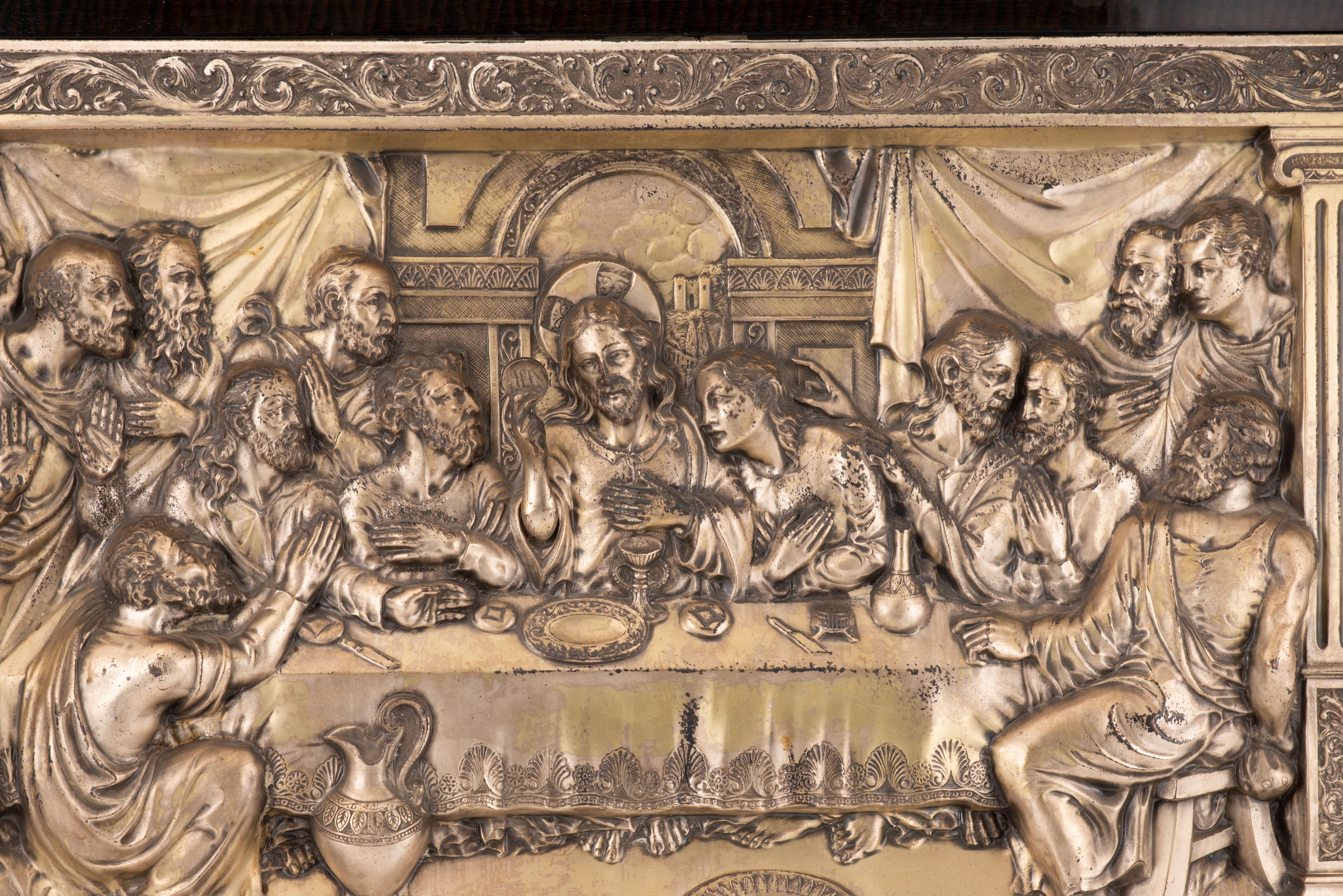 Last Supper. Silver-plated metal, wood. Spanish school, mid-20th century. 
Wall painting with a silverplated metal relief depicting the Last Supper (title in the lower area), with Christ in the centre of the table and the composition, the Apostles