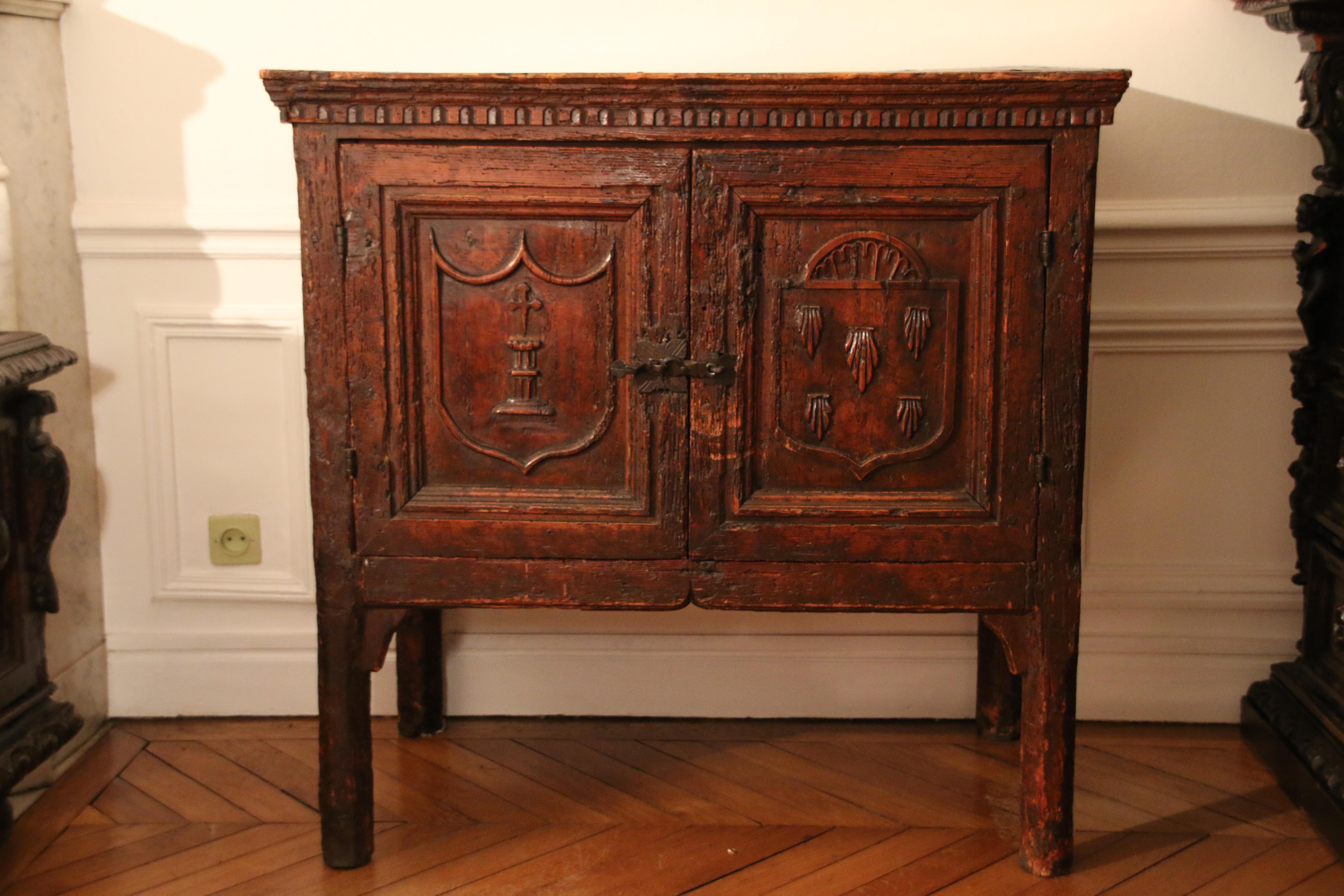 Standing on a four high feet this sacristy cabinet opens with two door-leaves. The lateral side panels bears a finely preserved linenfold decor. The cabinet’s interior is painted in dark red.

On both door-leaves are carved what appears to be a