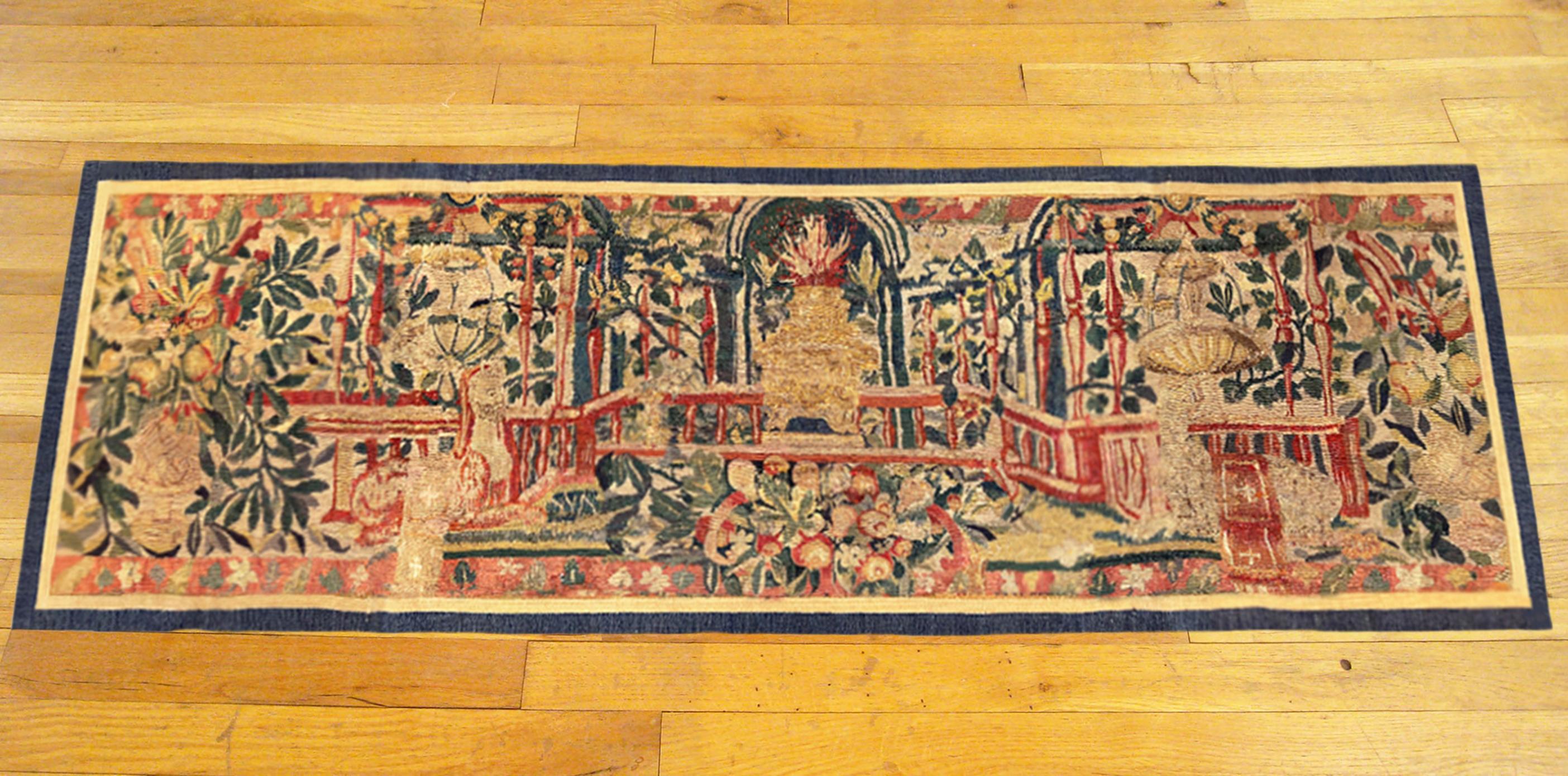 A late 16th century Flemish historical tapestry panel. This horizontally oriented decorative tapestry panel depicts a stylized staircase at center, with flowers and leaves throughout, as well as lanterns and other elements. The central area is