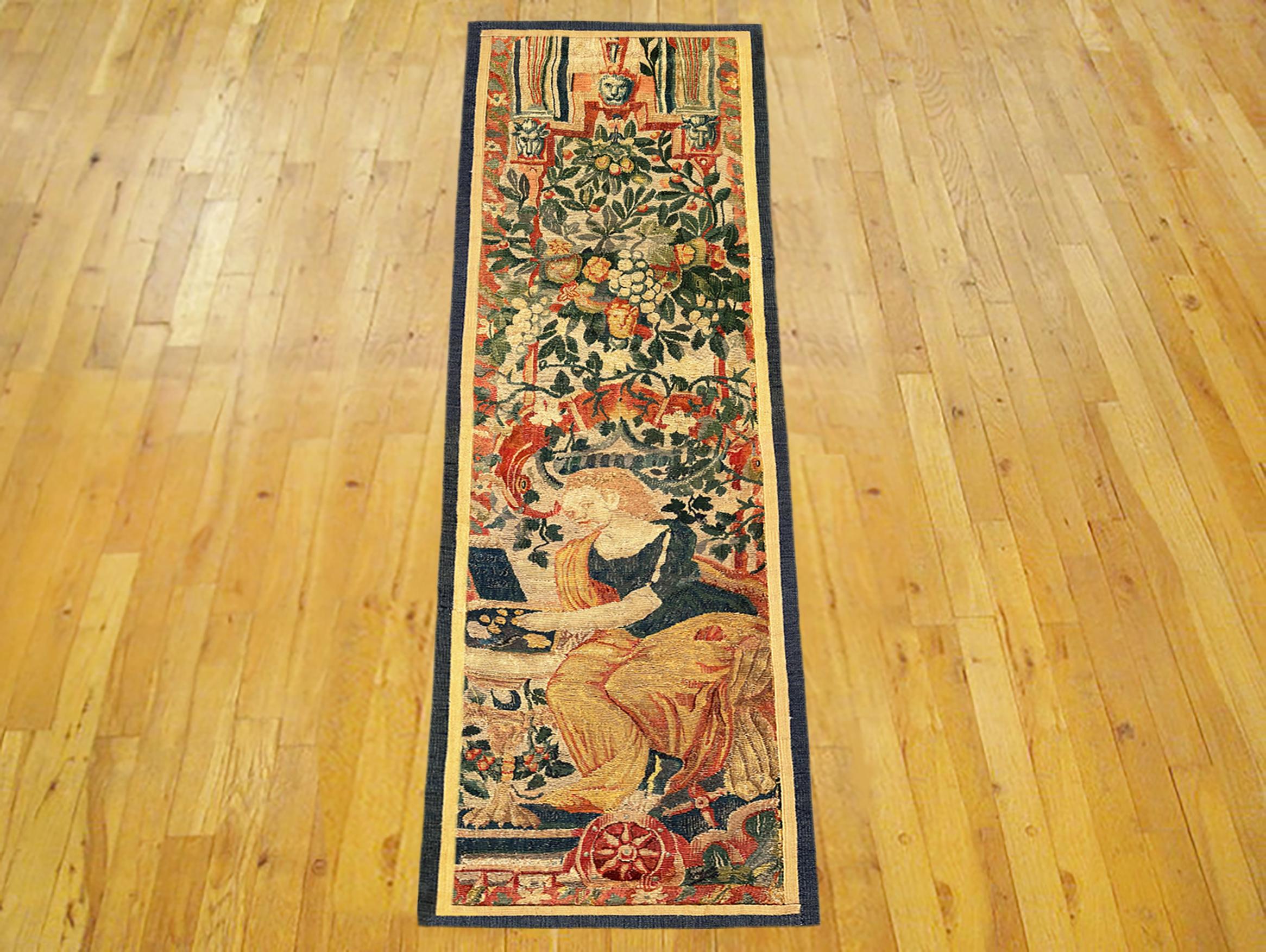 A late 16th Century Flemish Historical Tapestry panel. This vertically oriented decorative tapestry panel depicts a female figure at bottom, sitting within an elaborate floral reserve, with flowers and a portion of an arch at top. The central area