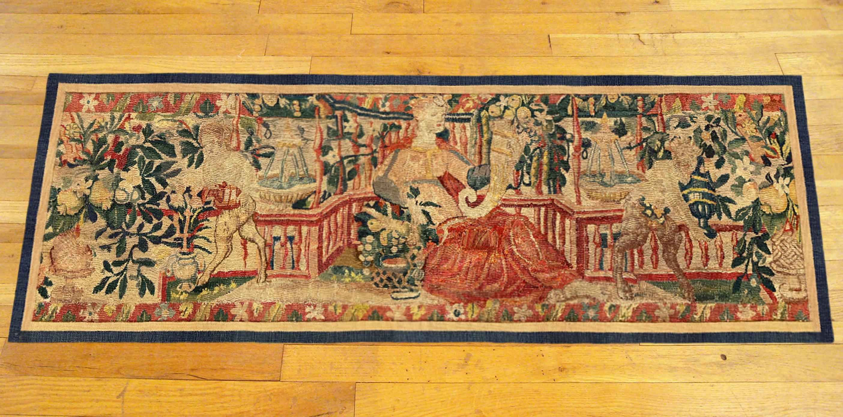 A late 16th century Flemish mythological tapestry panel. This horizontally oriented decorative tapestry panel depicts a female figure at center, holding a cornucopia in one hand, with satyrs flanking her at both sides, within a setting of flowers