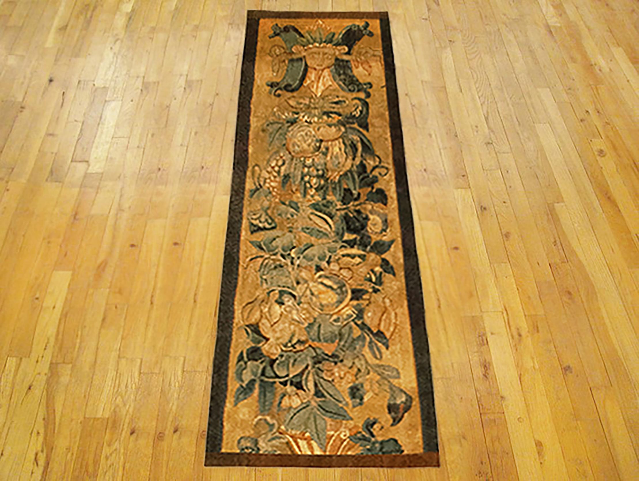 A 16th century Brussels Historical Tapestry panel. This vertically oriented decorative tapestry panel depicts a scrolling foliate design, with a grotesque and a coat of arms at top, and with ribbon ties and acanthus leaves below. The central area is