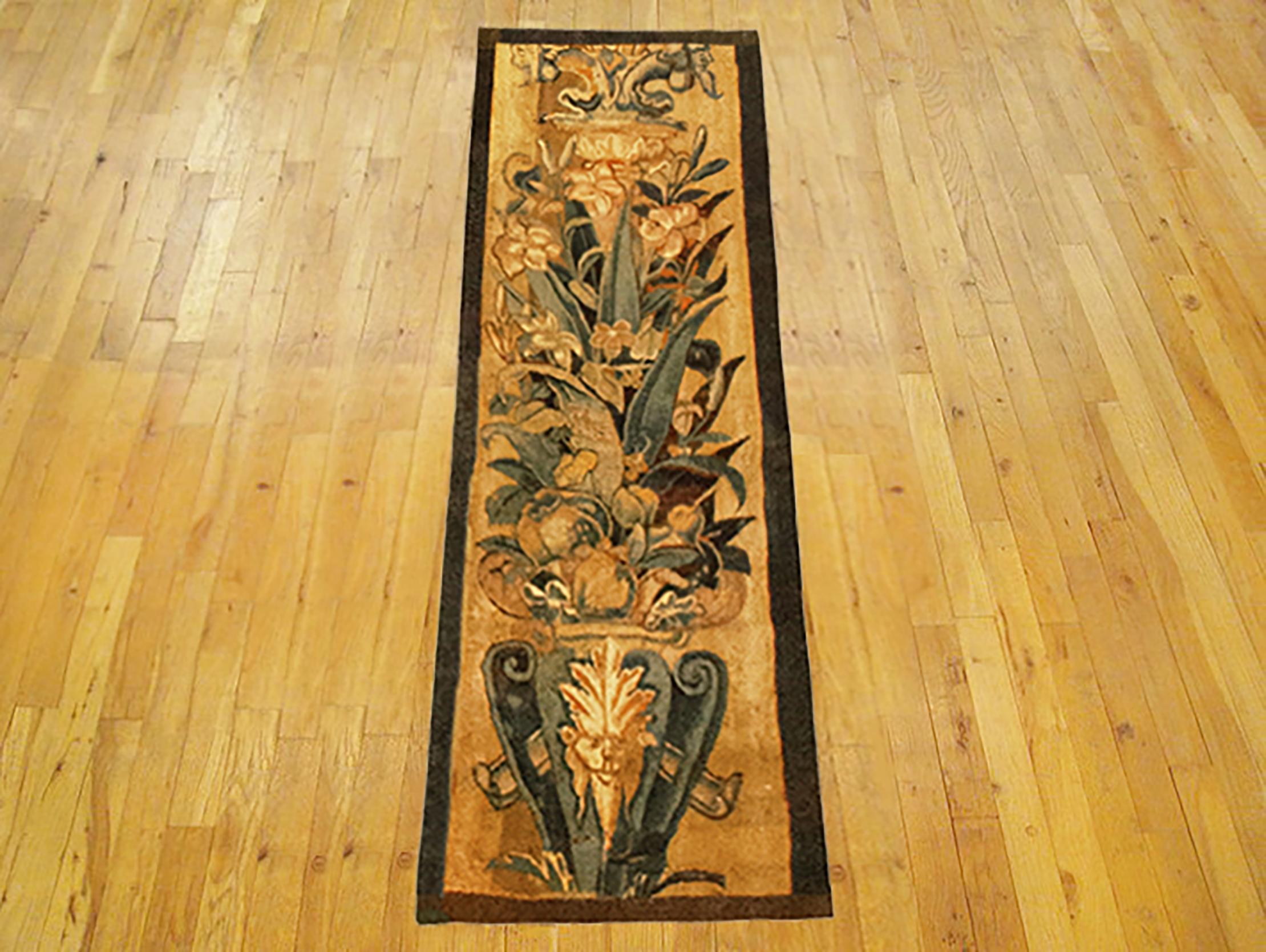 A 16th Century Brussels Historical Tapestry panel. This vertically oriented decorative tapestry panel depicts a scrolling foliate design, with a grotesque and a coat of arms at bottom, and with flowers and a vase above. The central area is enclosed
