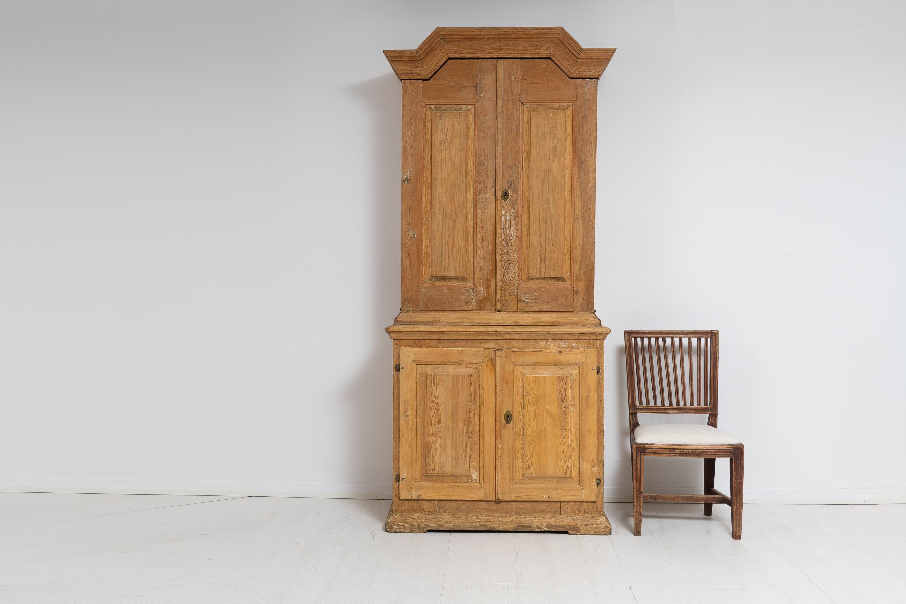 Late 1700s Swedish country house cabinet in baroque style. The cabinet is in two parts and hand-made in Sweden. On the outside the aged wood is visible with the grain and structure of the wood clearly seen. The cabinet is well-made with a solid