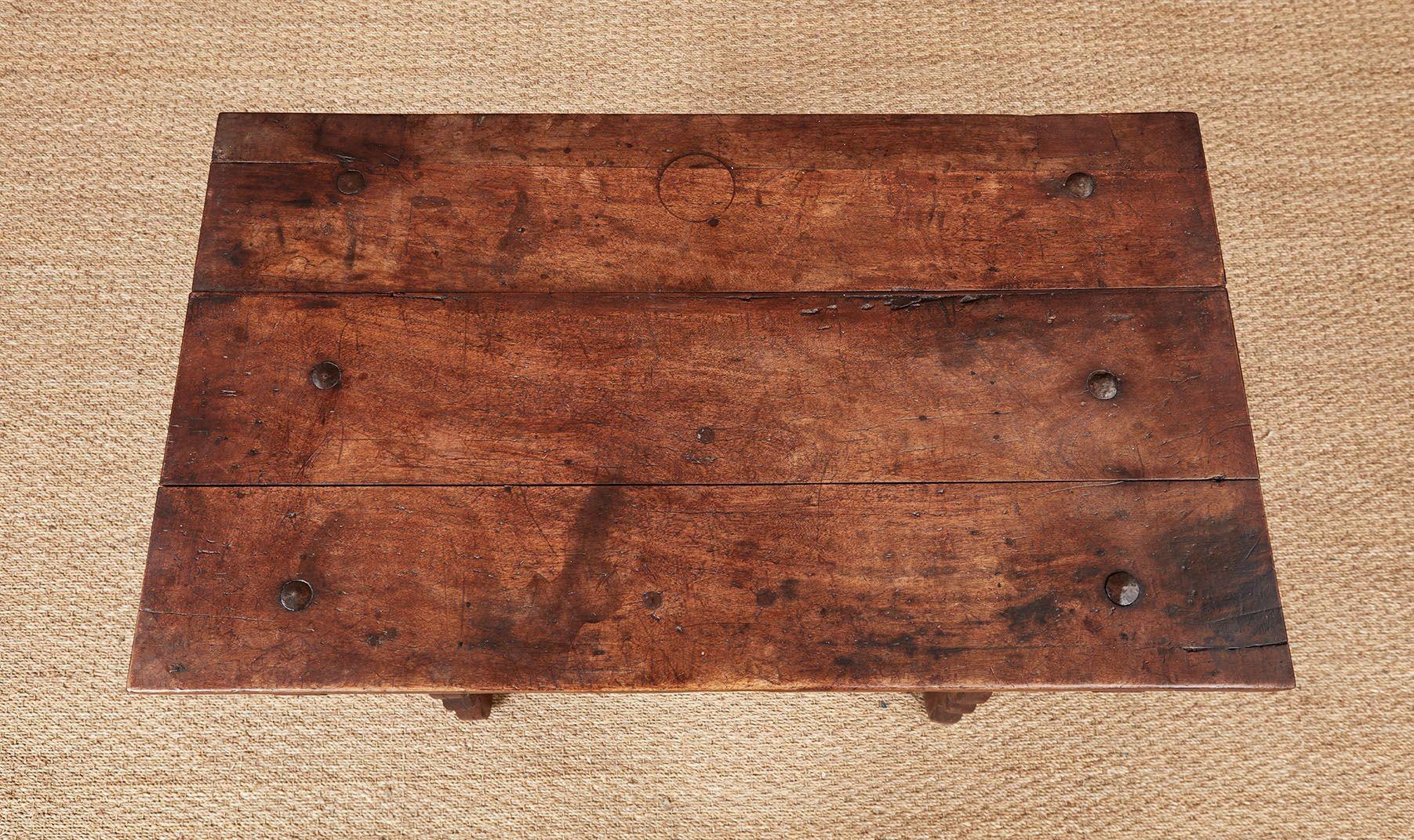 A late 17th century Italian side table in lovely patinated walnut having a rectangular top attached to the frame with six domed iron through bolts and resting on outrigger supports, a cross-hatched decorated drawer front over a scalloped apron, and