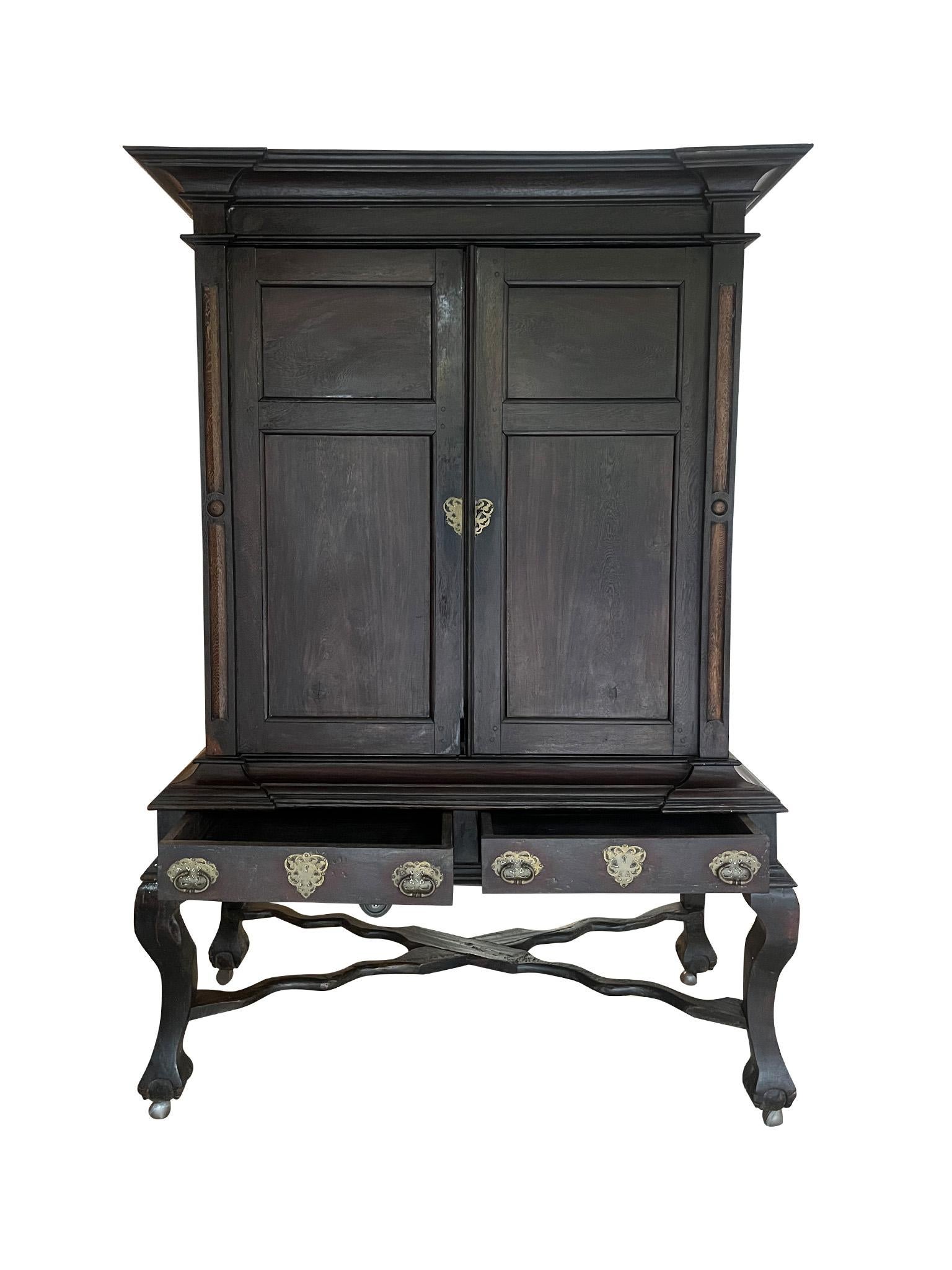 Fantastic and unusual Antique Dark Oak Linen Cabinet. Constructed during the late 17th century, this linen cabinet was built in solid oak and comprised of two pieces. The bottom components design features a wavy x-base stretcher, two storage