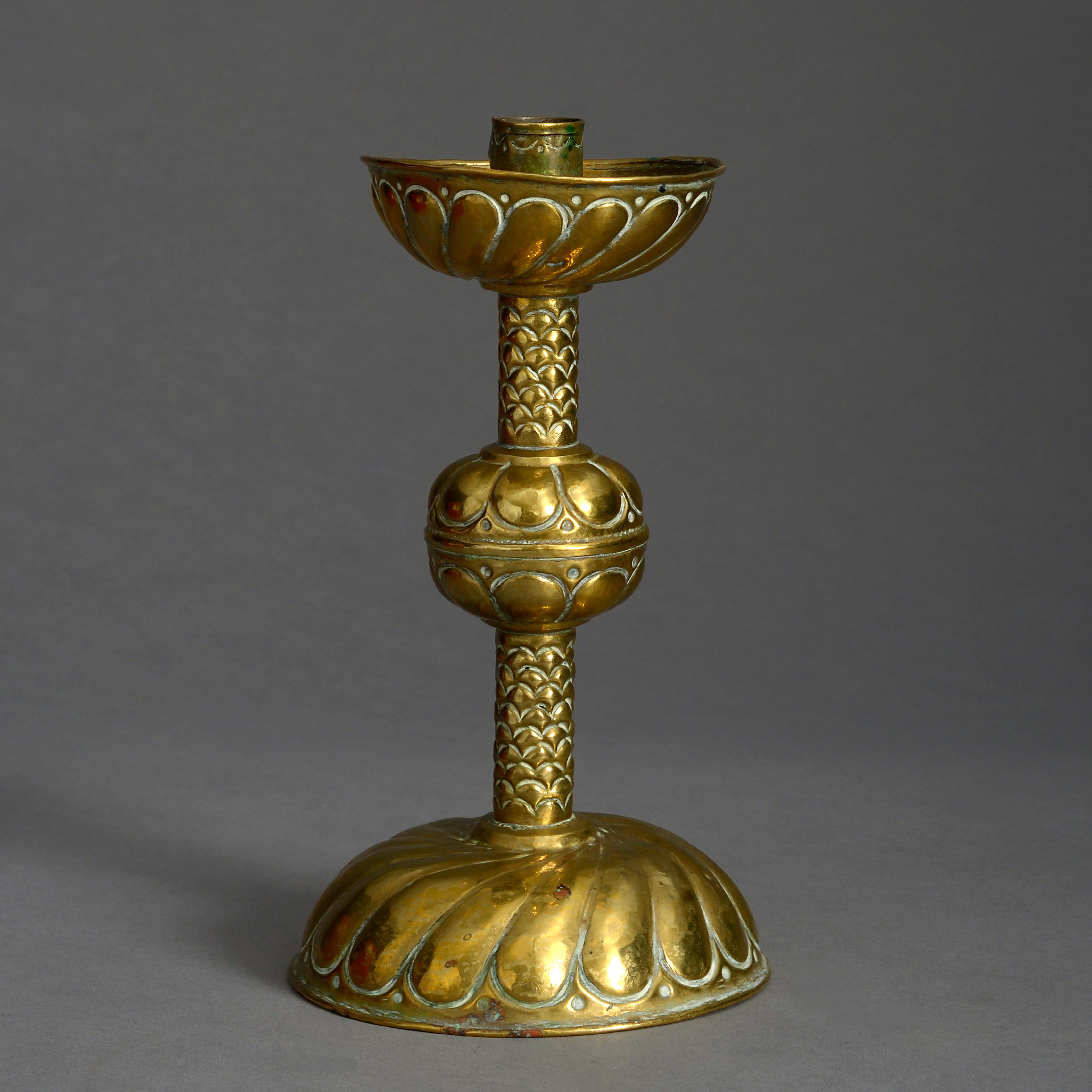 A late 17th century brass candlestick, the dished top above a stem with fish scale decoration, set upon a gadrooned base.