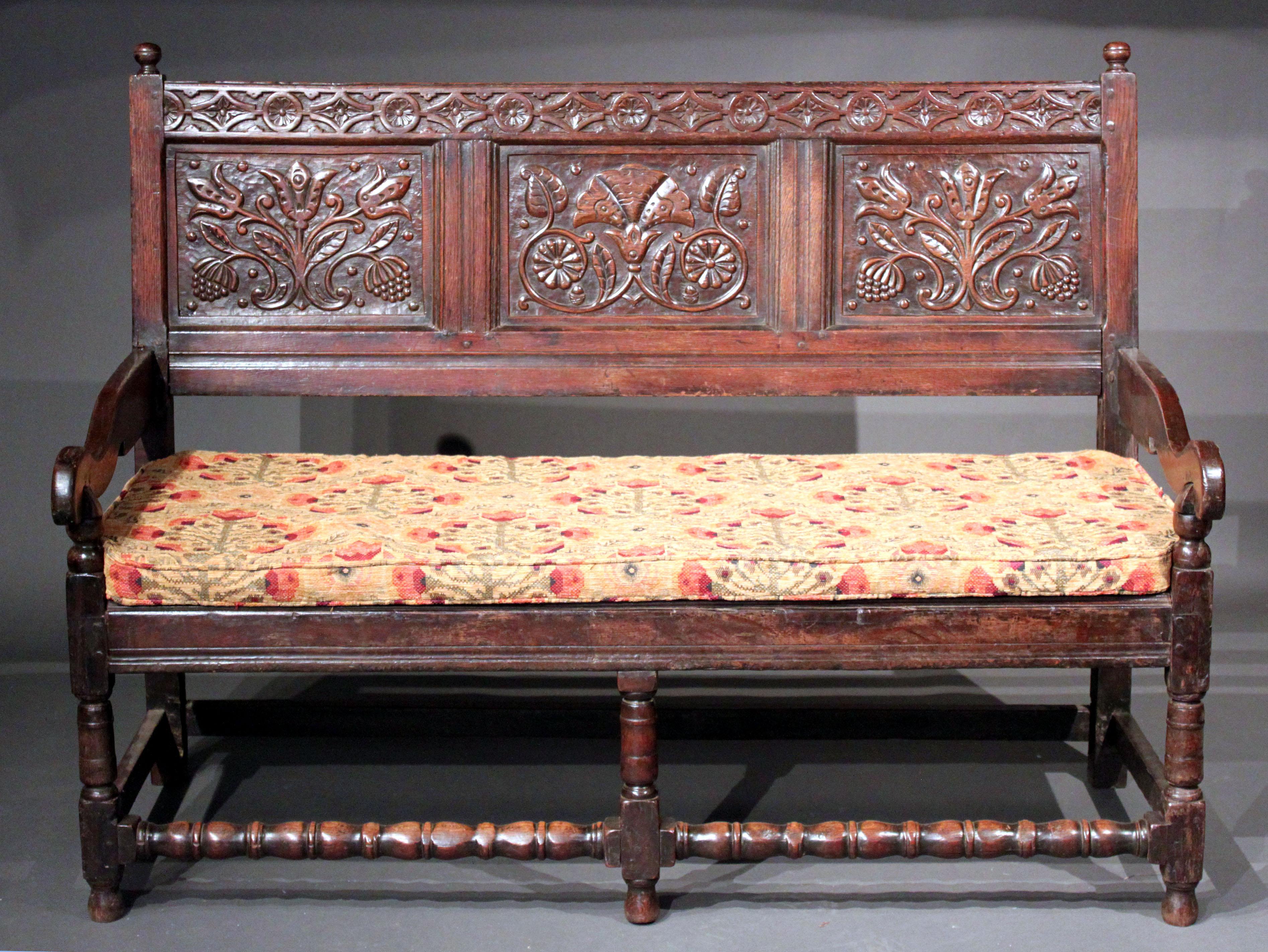 A late 17th century oak settle with well carved back and good original colour and patina; small restorations including a repaired chip and metal brackets under the front seat rail, recent tongue and grove boarding under the seat; it might originally