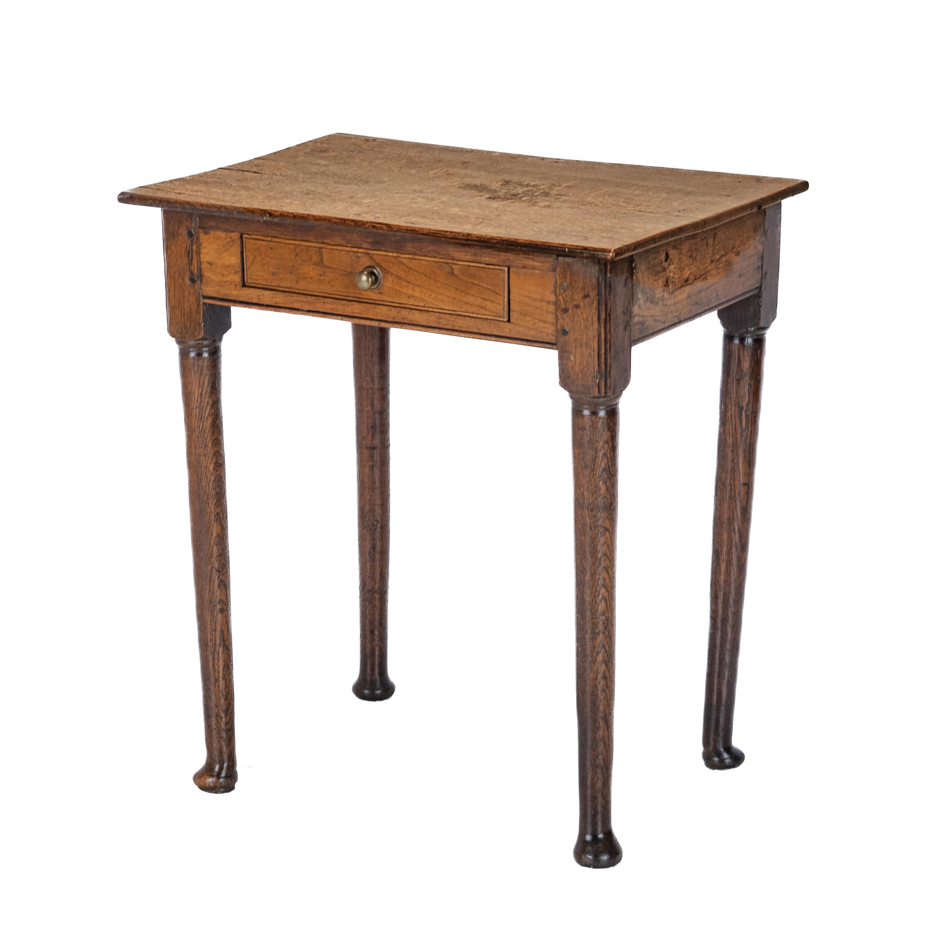 A late 17th century elm and oak, pad foot small country side table with drawer. An oblong shaped, associated plank solid oak top of similar period. Plain elm frieze with the later addition of a single drawer with brass knob handle, made from the