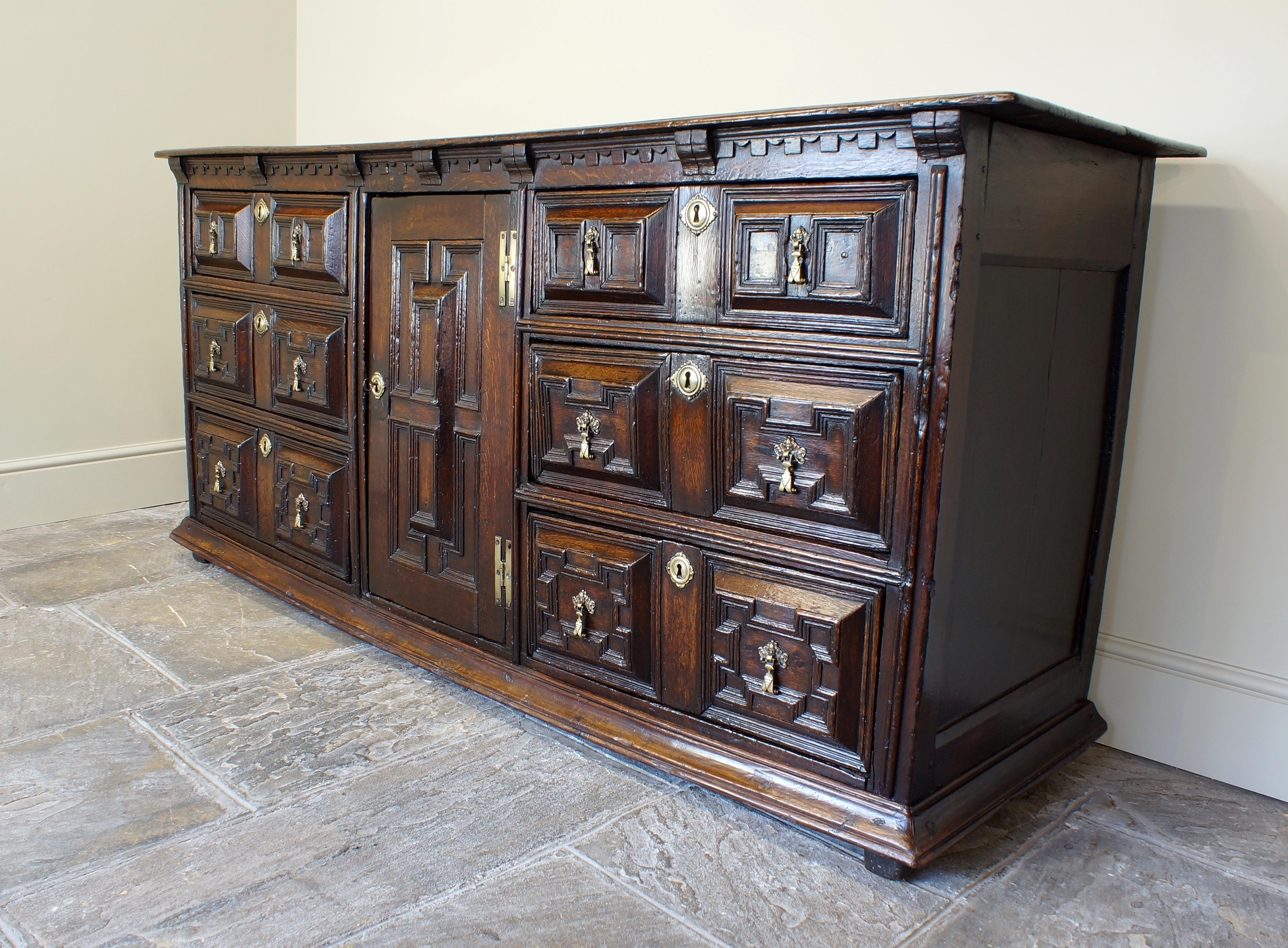 Superbe meuble de service en chêne du 17e siècle
une présence extraordinaire. Le dessus à deux planches est surmonté d'une porte d'armoire centrale, flanquée de deux rangées de tiroirs à coussin et à moulures géométriques. Le fond de la commode est