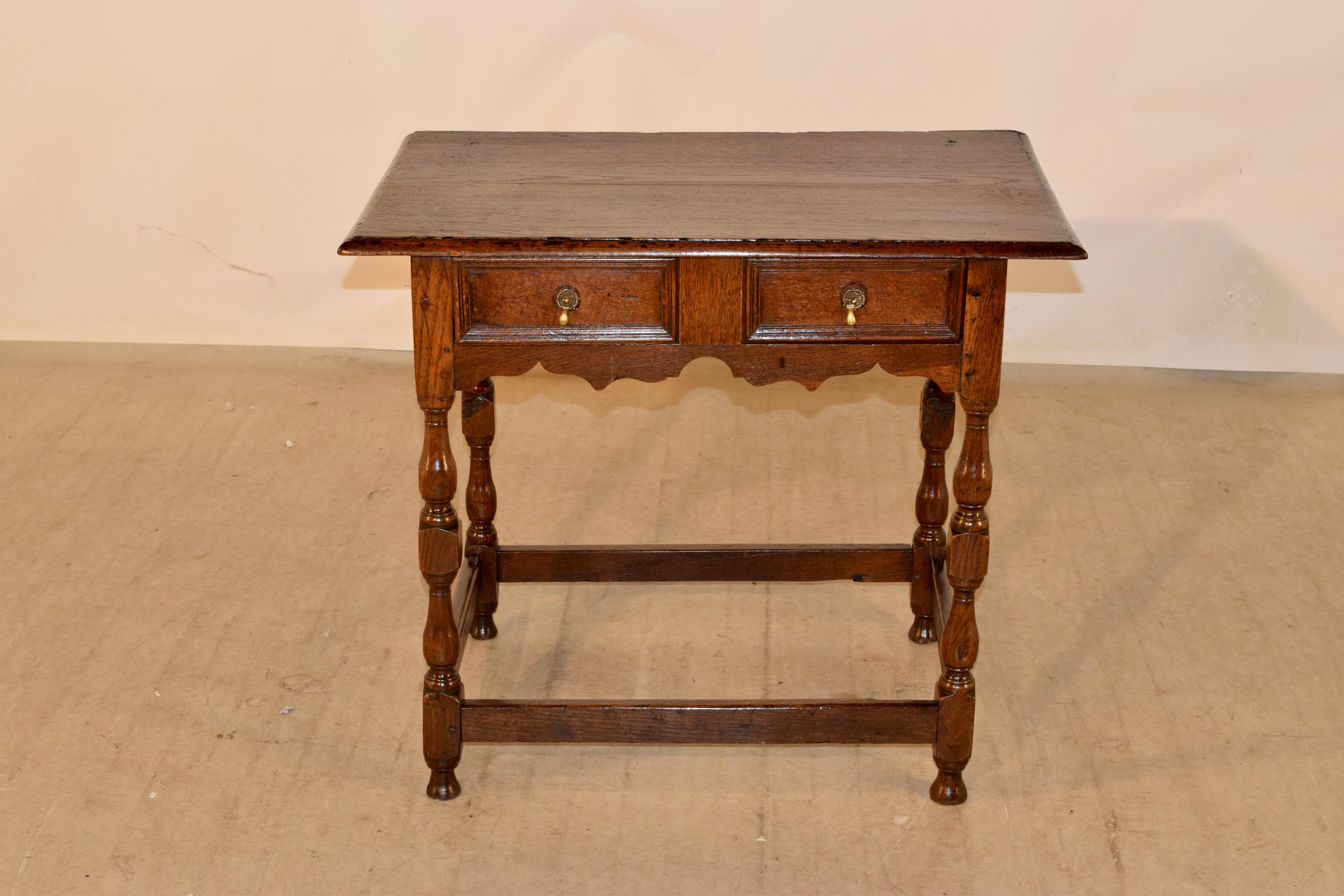 Late 17th century oak side table from England with a two board top that has a beveled edge around the top, following down to simple sides and a single drawer in the front with a lovely hand scalloped apron. the table is supported on hand turned
