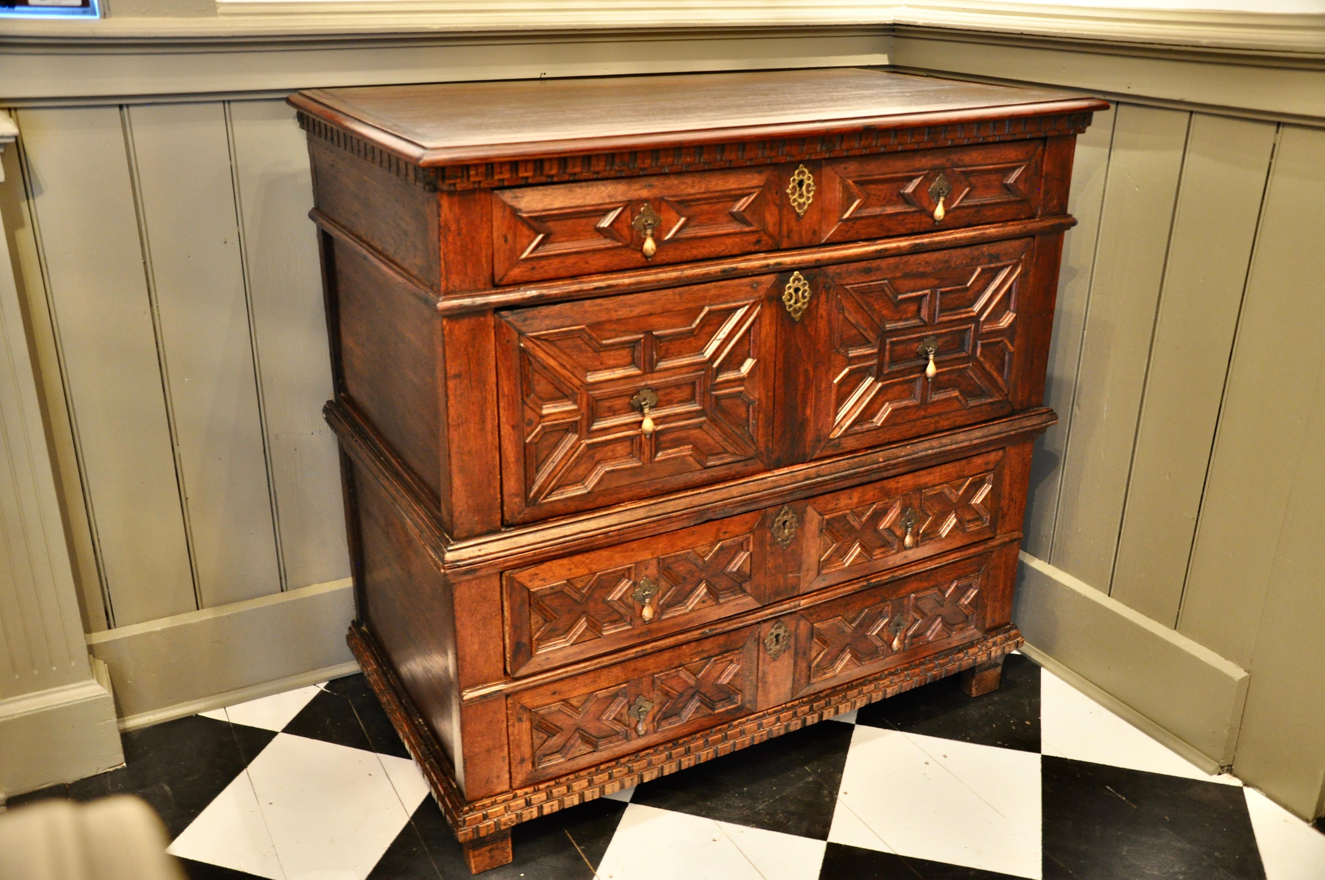 An English red walnut and oak James II chest of drawers. Geometric patterning. Drawers work well. In two parts. Feet extended. Minor restoration. Good old or original waxed finish.