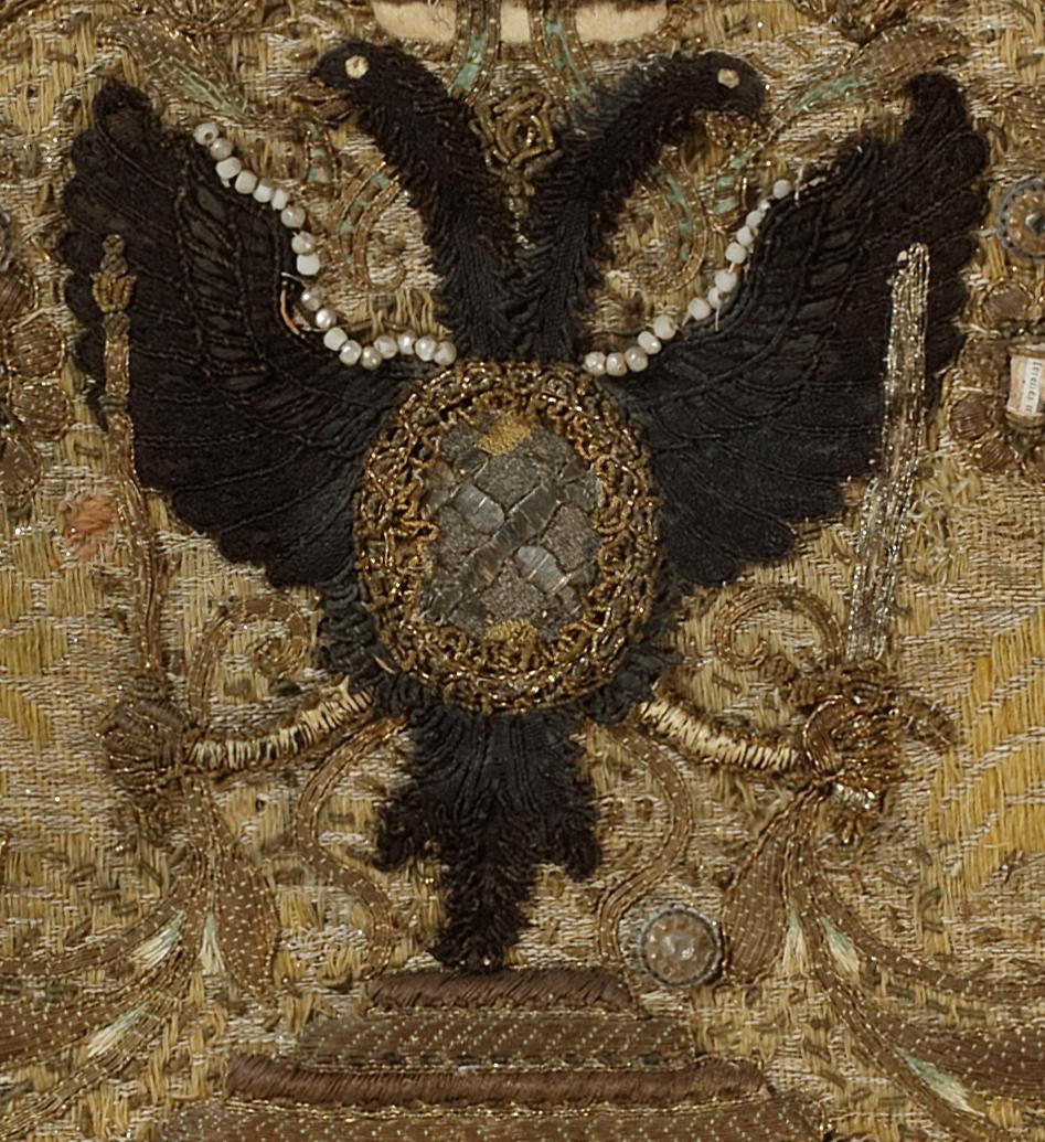 This embroidered picture is applied with beads, the embroidery with scrolling leaves, flowers and central double eagles head crest surmounted by a coronet, in a modern gilt rectangular frame.