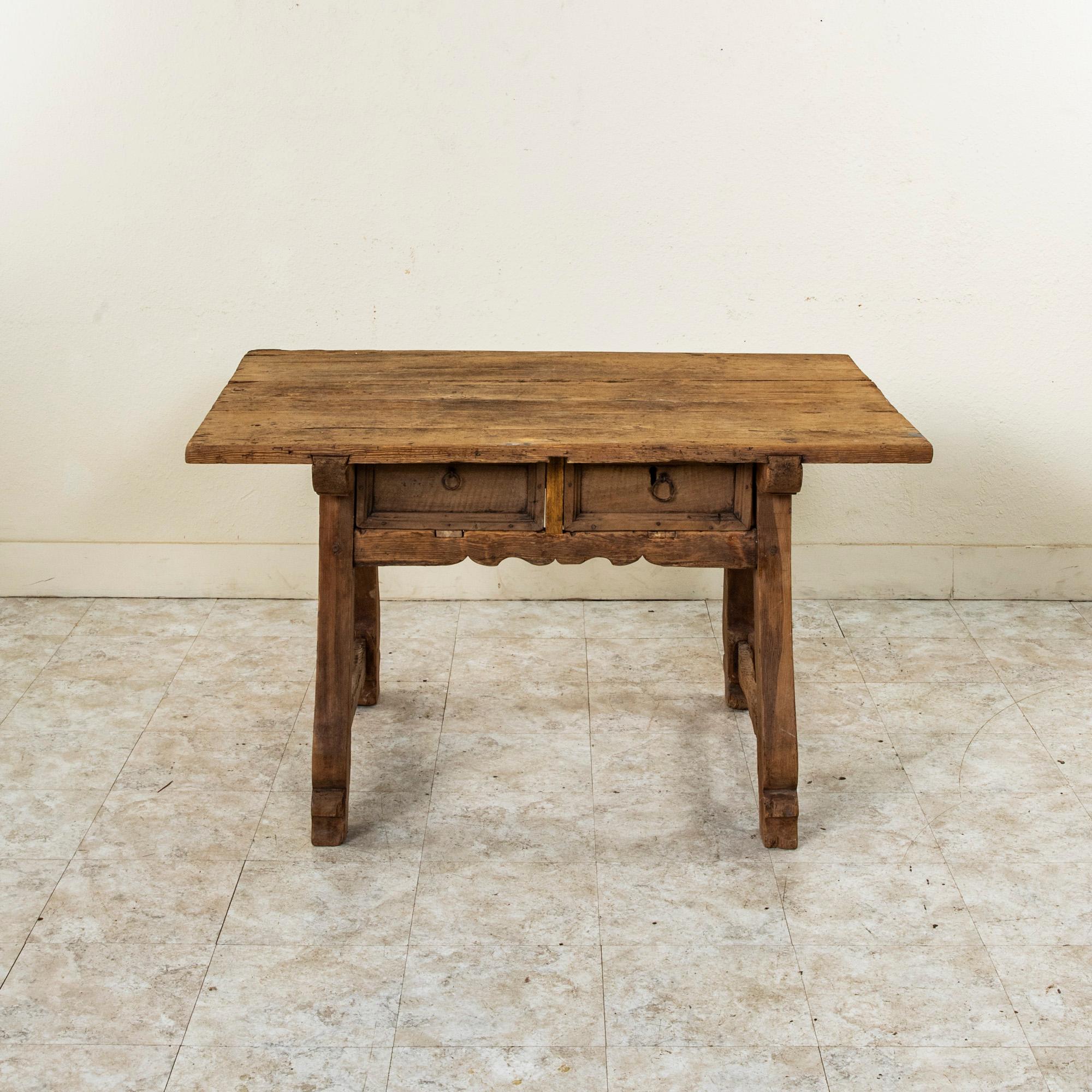 Cette table à écrire rustique en pin, fabriquée artisanalement, provient de l'Auvergne, une région montagneuse du centre de la France. Créée par un éleveur de chèvres au XVIIe siècle alors qu'il gardait ses moutons, cette table est fabriquée à