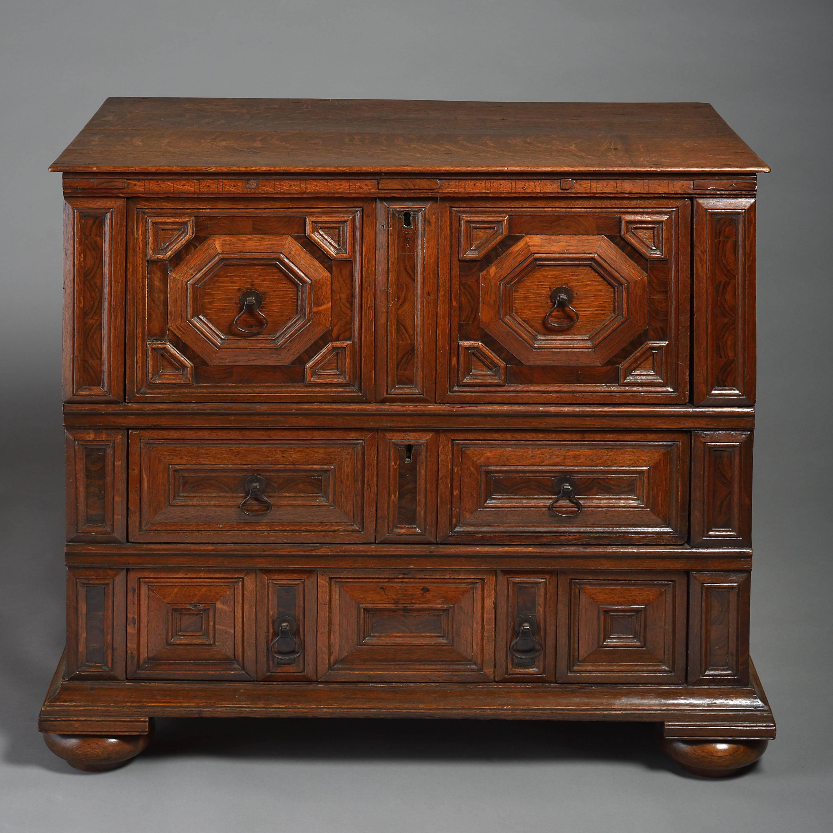 A late 17th century Charles II period oak chest, the overhanging top above three graduated drawers with geometric mouldings and olivewood veneers, all retaining the original handles and raised on bun feet.

This chest in constructed in two halves,