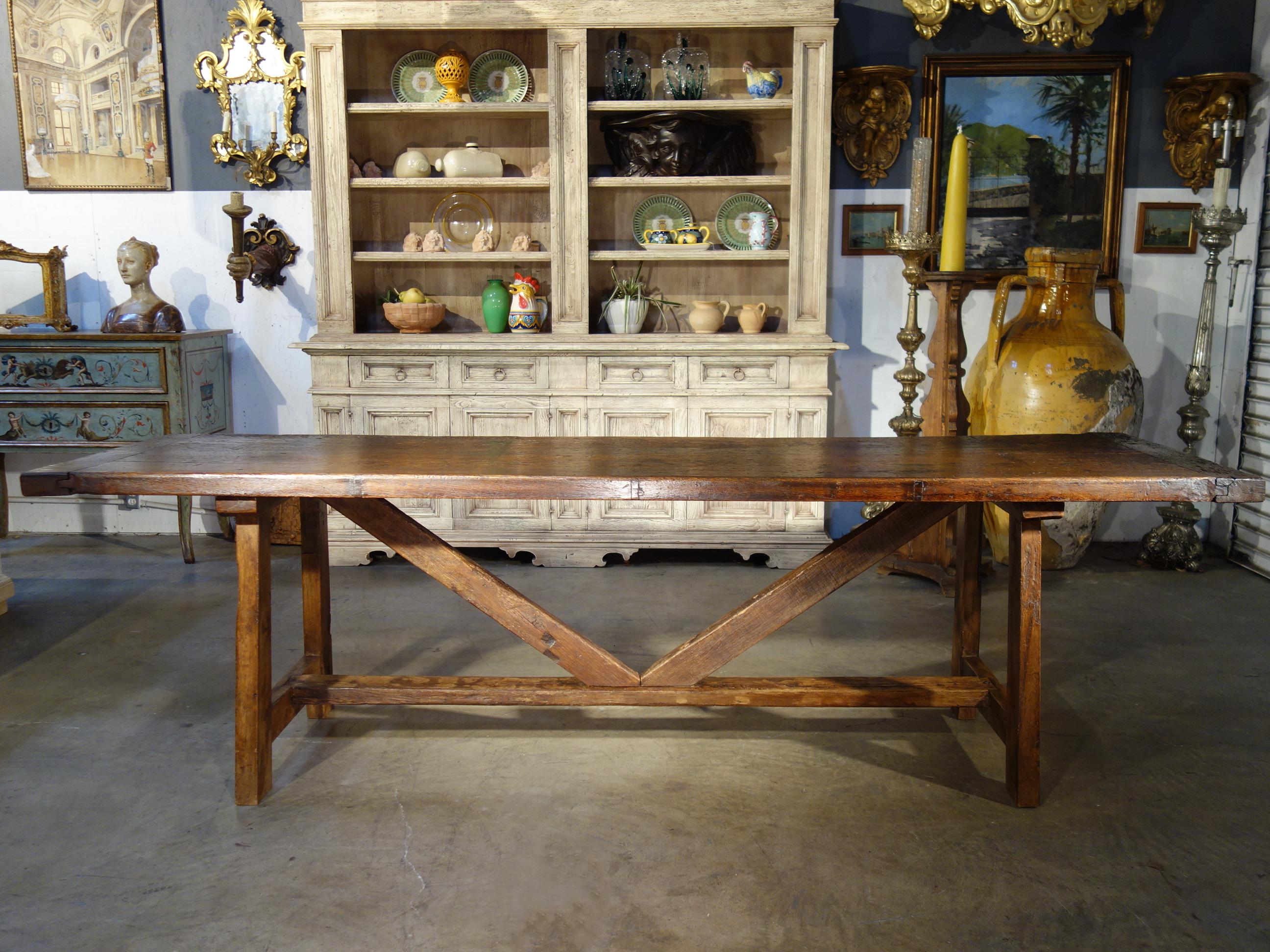 Late 17th Century Italian chestnut Frattino style antique trestle table features 2 ancient solid top planks with end frames, trestle base crosspieces and forged iron joinery pins. With is superior details including dovetail joinery,  present a fine
