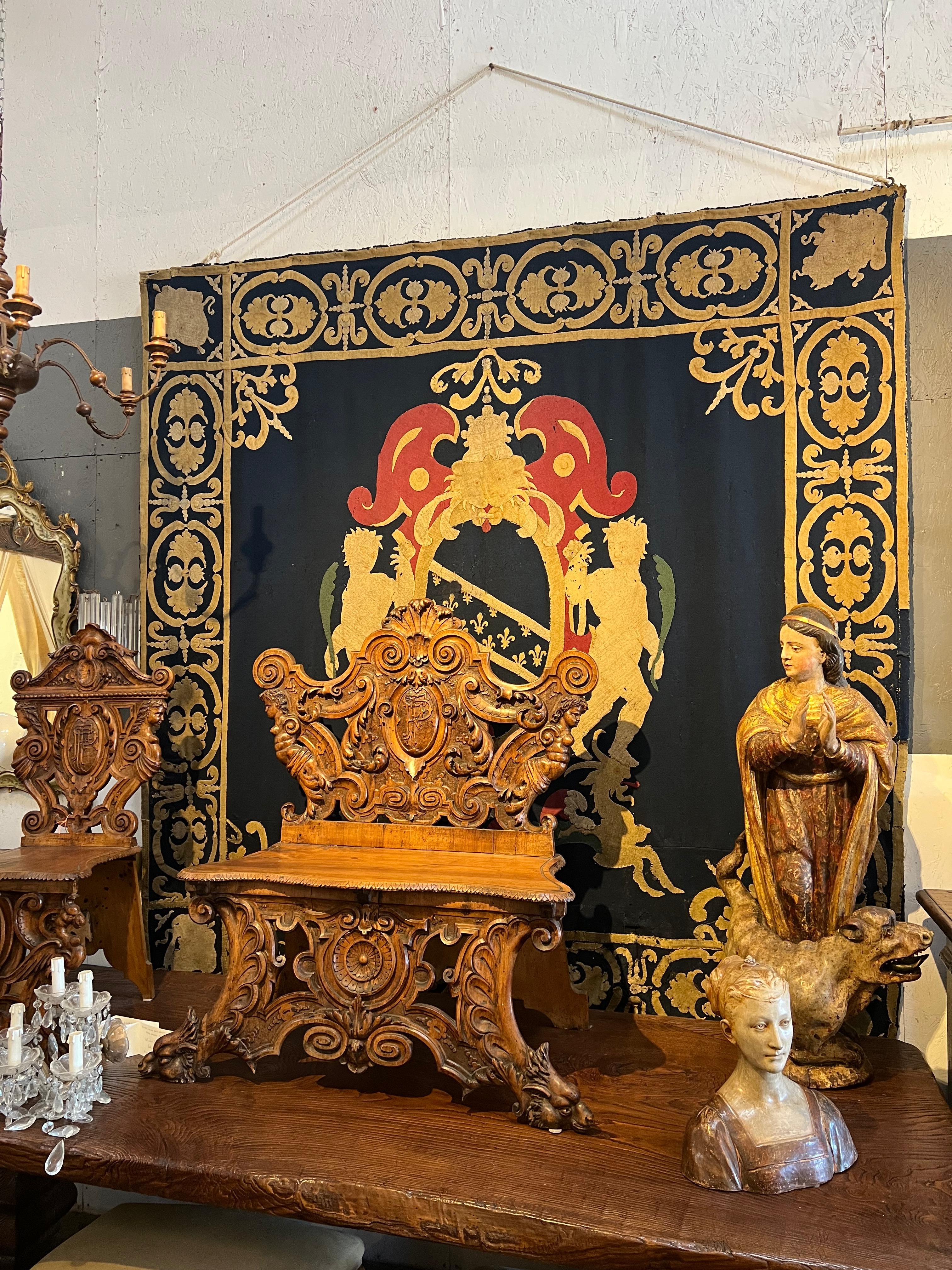 Dieser Wandteppich ist im aristokratischen Stil gehalten und zeigt ein heraldisches Wappen, das aus verschiedenfarbigen Wollstoffen besteht, die als Collage auf blauem Wollstoff angebracht sind. Lucchese (Lucca) Manufaktur aus dem späten 17.
