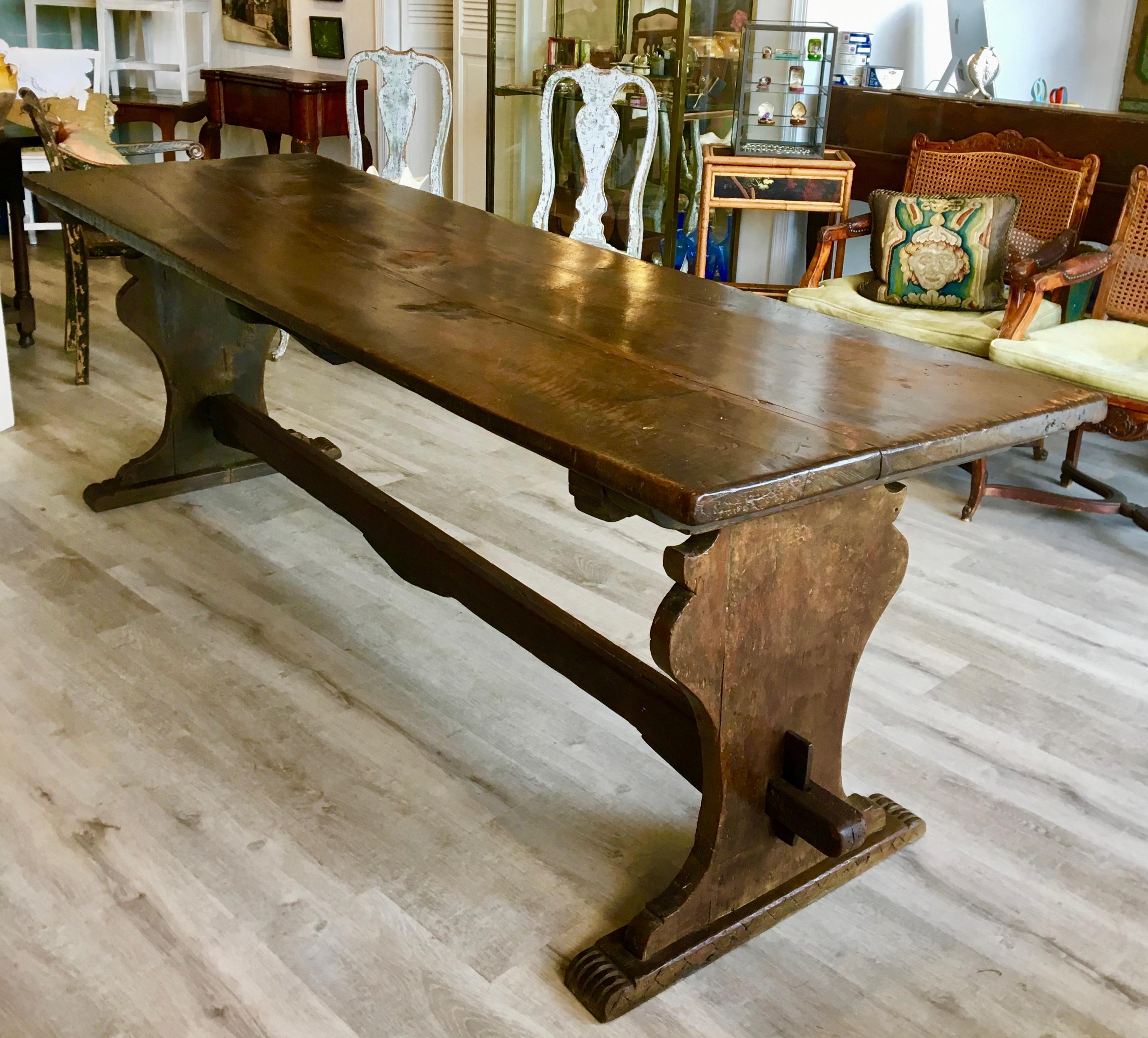 Late 17th Century Italian Walnut Dining Refectory Table, with extraordinary single-plank top, over shaped supports and a wedge-pegged cross brace. The rare piece is in excellent condition and has a rich, glowing patina.