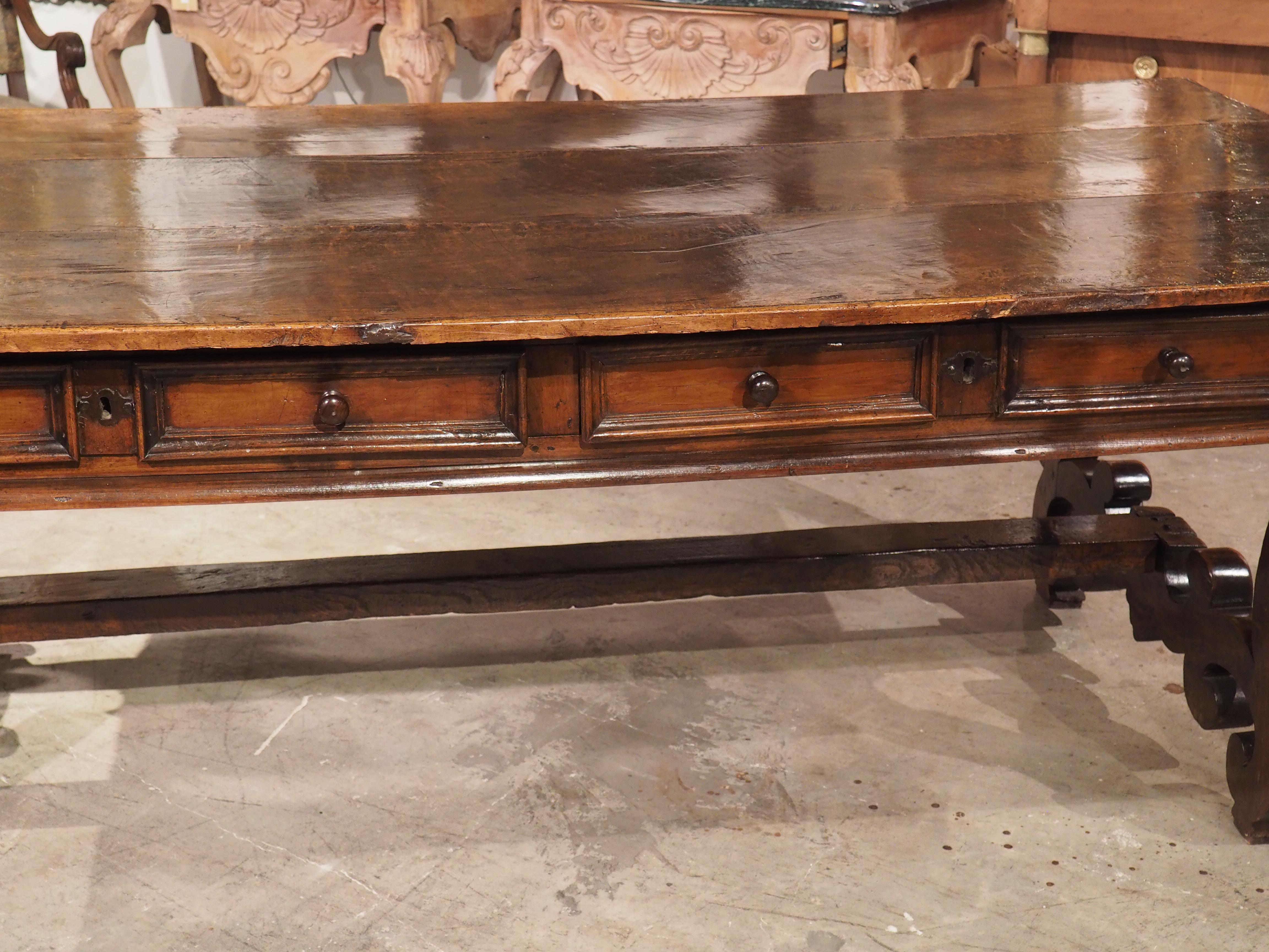 This majestic library table was hand-carved in Italy during the late 1600’s. Three planks of rich walnut wood comprise the top that has been carved with a thin recessed molding along all four sides. A slight bend to the three hundred plus year old