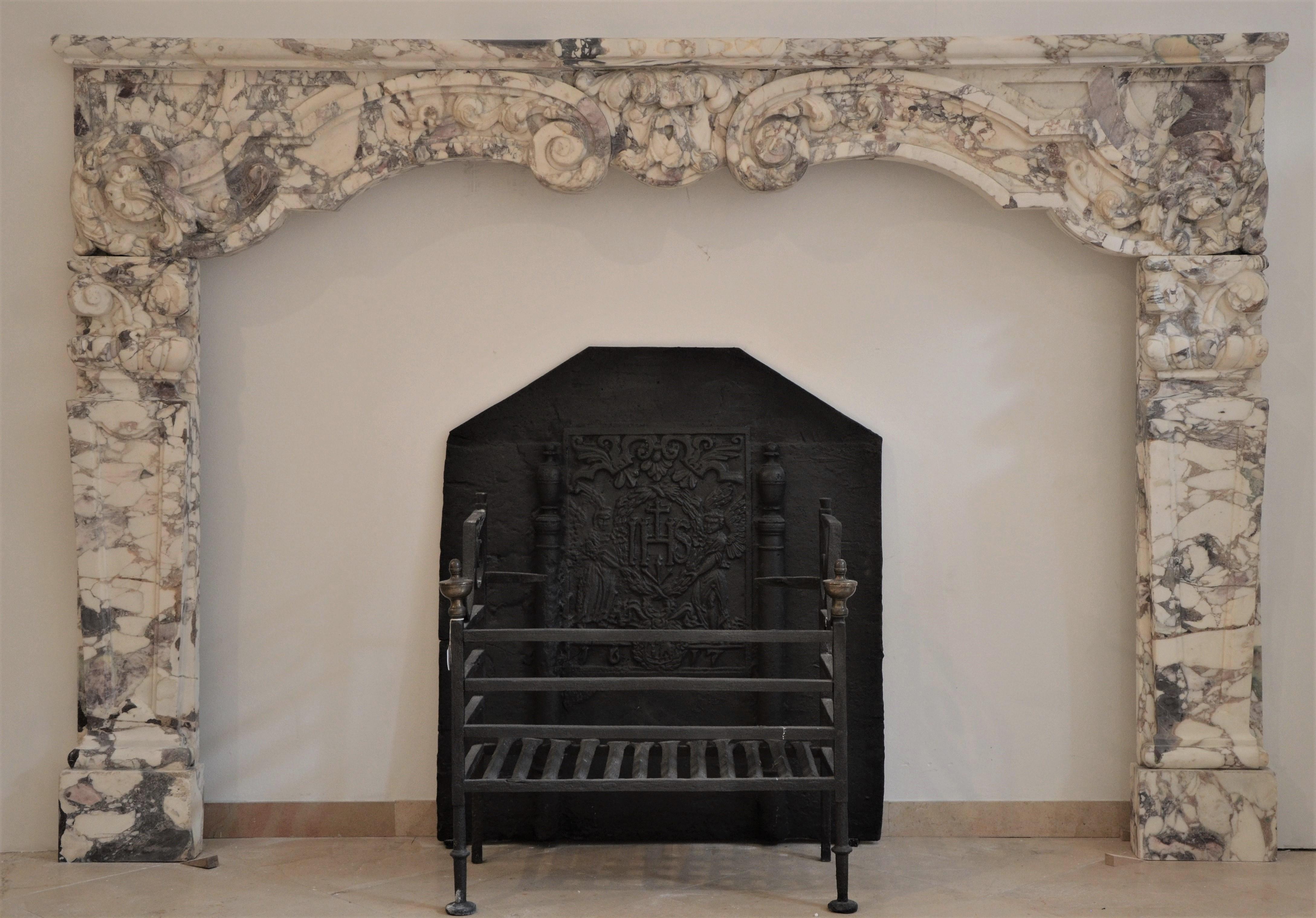Unique and regal late 17th century Dutch Louis XIV fireplace mantel.
This rare and large mantelpiece is executed in the finest Italian breche violet marble.

The boldly carved central keystone is flanked by beautifully scrolled floral decorations