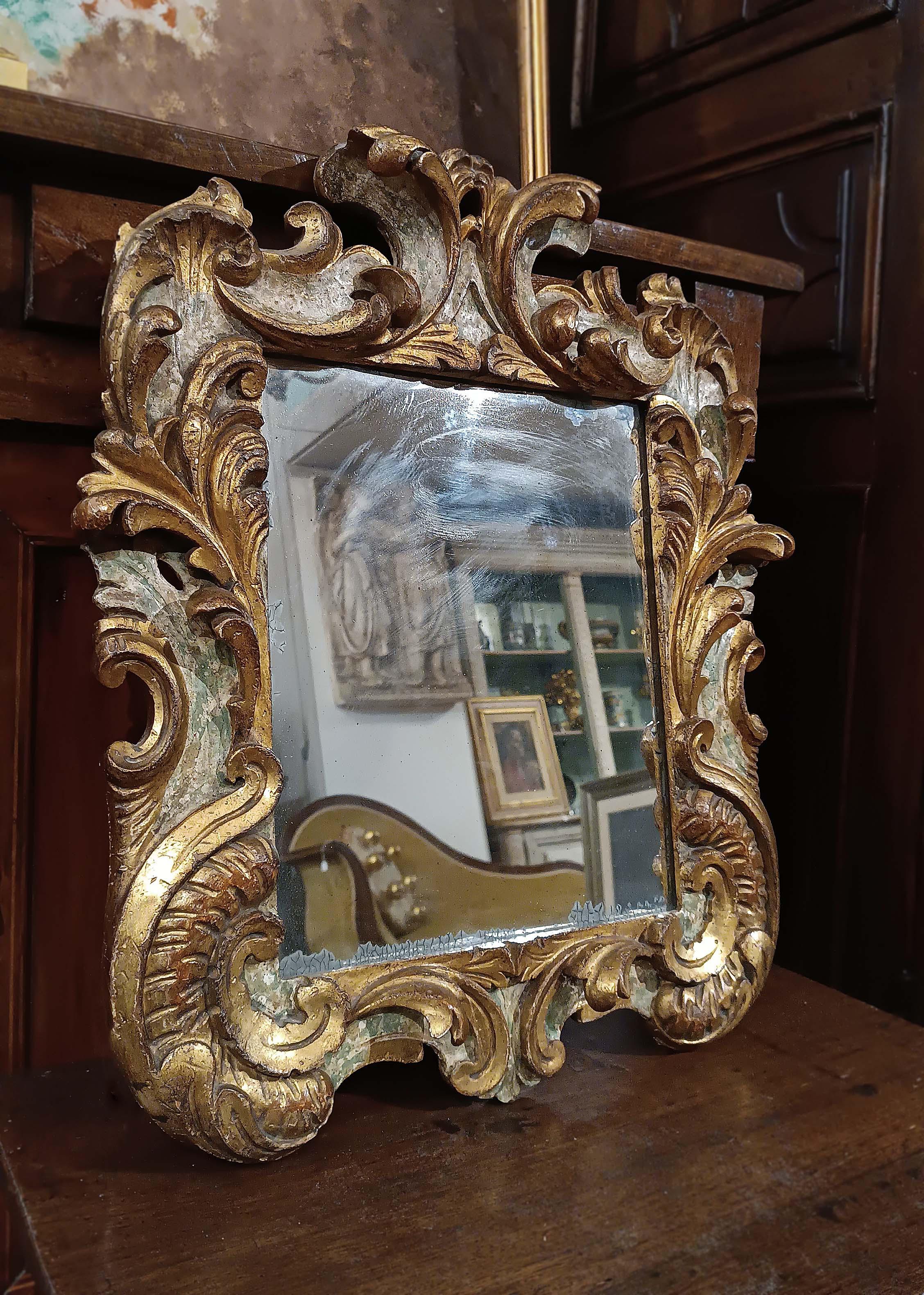 Beautiful medium-small mirror, made of carved wood and gilded with gold leaf, and painted in fake marble. The frame has vegetal curls that give a touch of refinement and class to the object. The mirror is in good condition and retains its