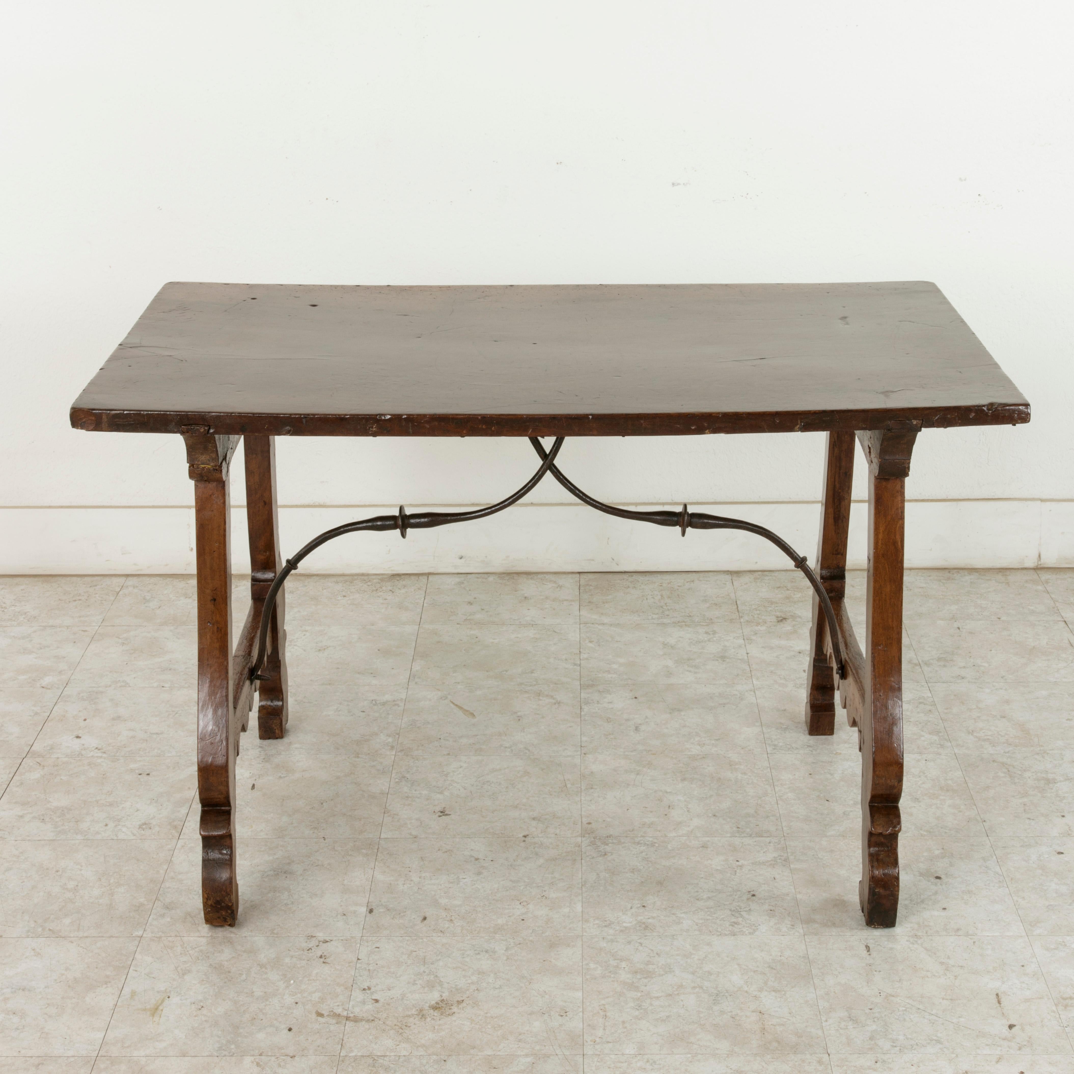 This late 17th century Spanish Renaissance writing table is constructed of solid walnut and features an impressive 30-inch wide top made from a single plank of walnut. The top joins the hand pegged base by means of a notched spline that run the