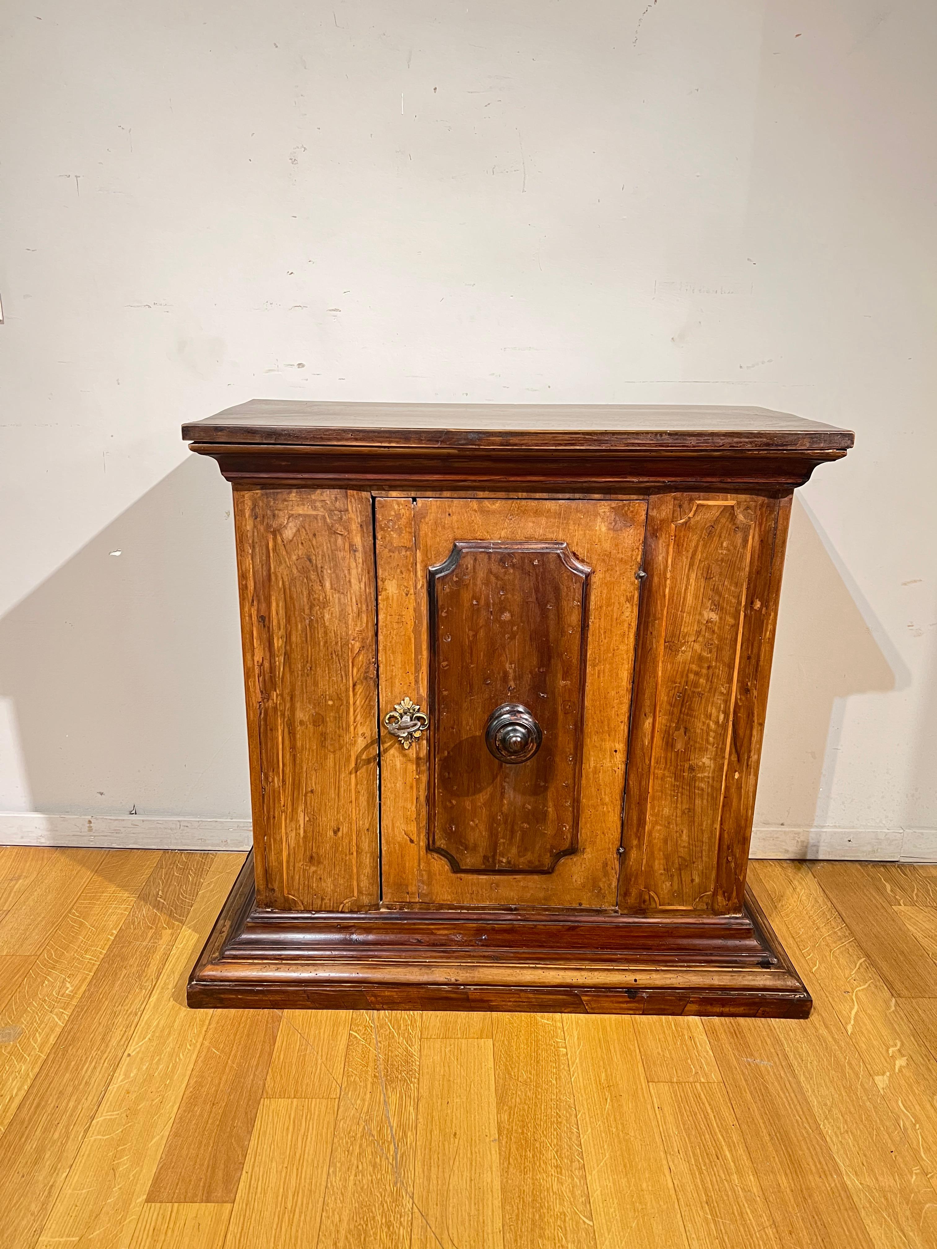 Beautiful small size sideboard in walnut embellished with fruit wood threads. An ashlar door on the front with a turned wooden knob, a gilt bronze escutcheon and an iron key.
Tuscan manufacture from the end of the 1600s.

MEASURES: cm 76x81x38.