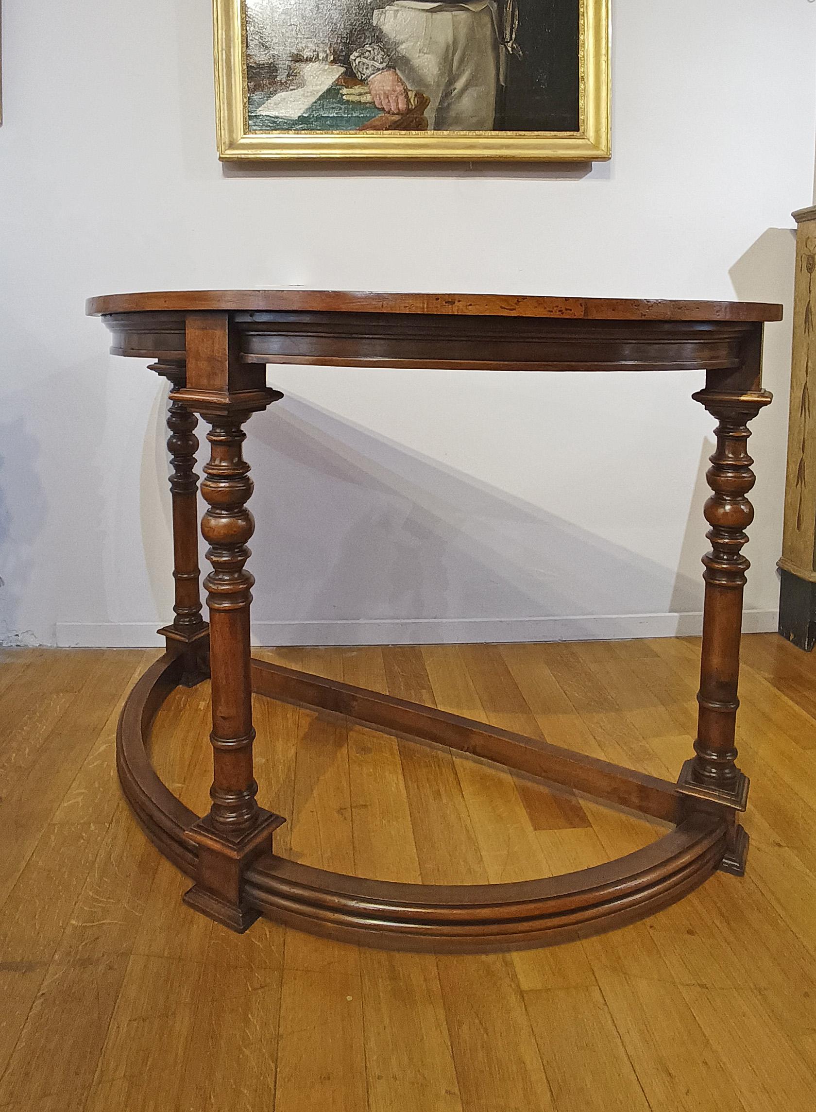 Eleganter handgeschnitzter halbmondförmiger Konsolentisch aus massivem Nussbaum. Der Konsolentisch hat drei gedrechselte Beine, eines an der Vorderseite und zwei an den Innenseiten, die ihm einen Hauch von Raffinesse verleihen, sowie halbrunde,