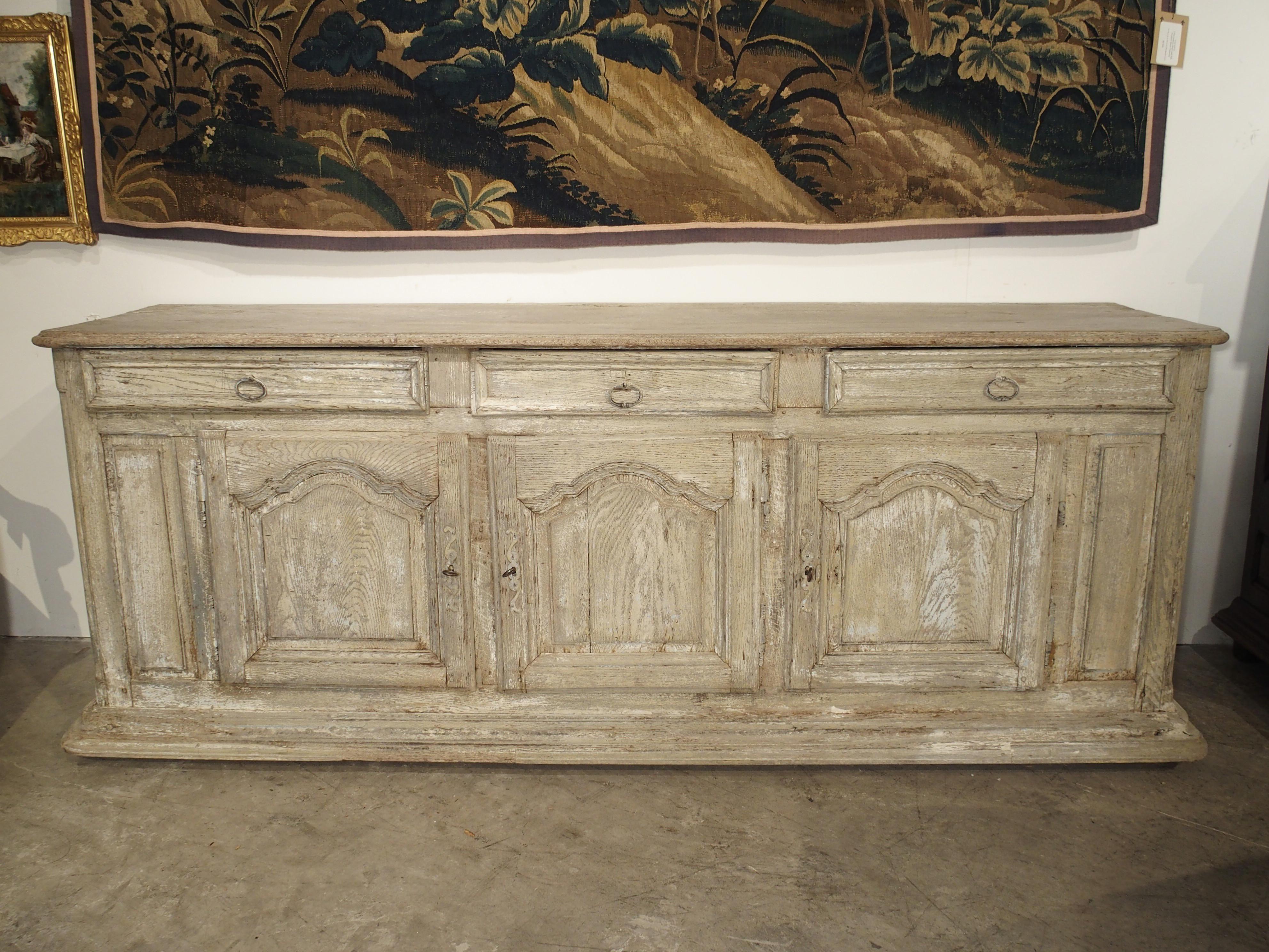From Burgundy, France, this late 1600s whitewashed oak enfilade has three drawers with drop pulls, and three cabinet doors with indented and raised panels to either side. It has been whitewashed over a pale blue paint at some point in its history.