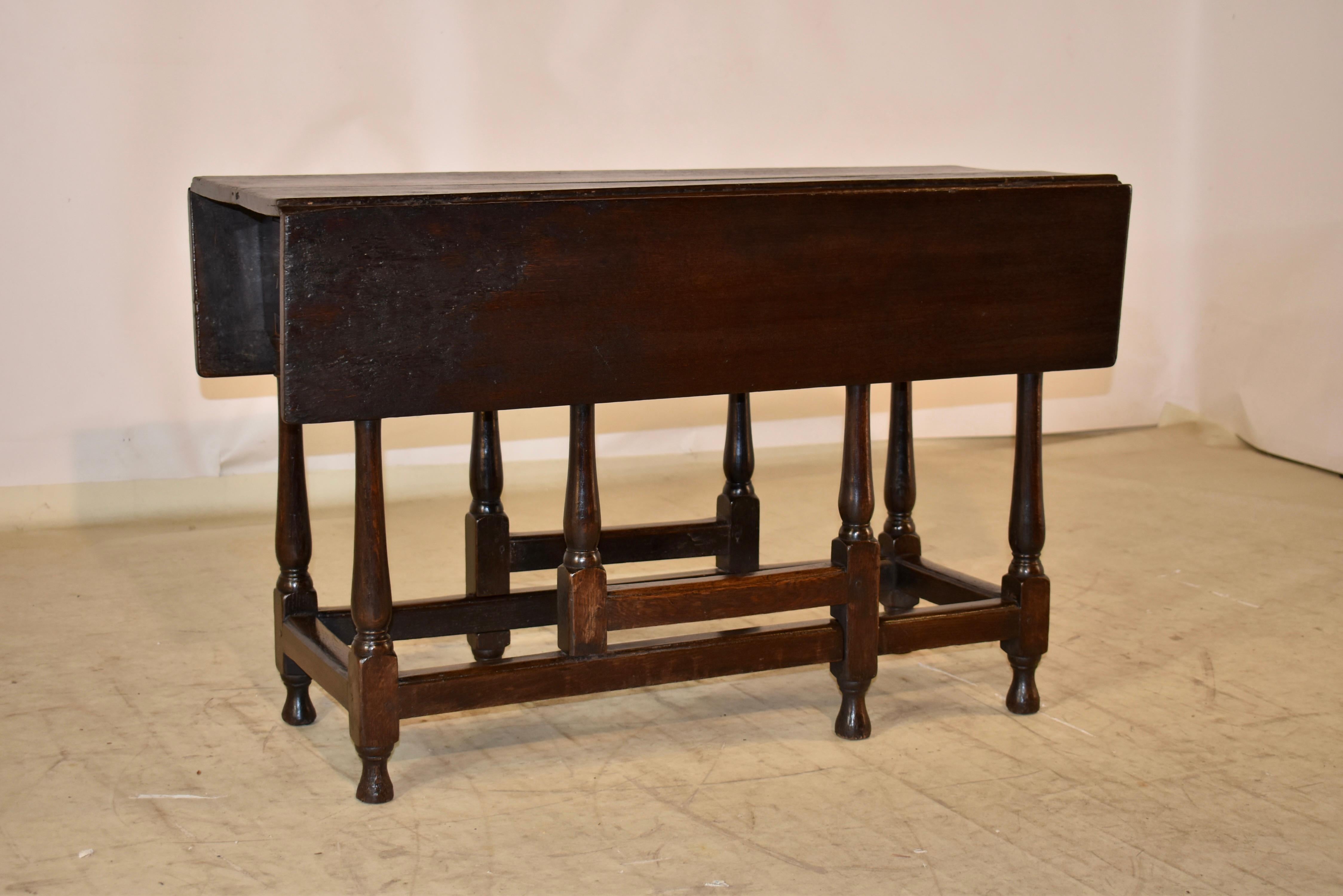 Late 17th - early 18th century oak table from England with two drop leaves.  The top is primitive, and is made from four boards.  The top follows down to a simple apron, which retains the original drawer.  The table is supported on hand turned legs