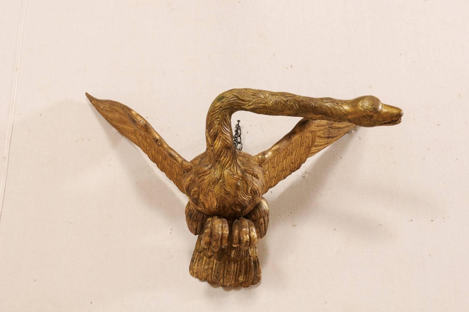 A late 18th-early 19th century Italian giltwood and carved swan. This wonderfully expressive antique swan from Italy features outstretched wings, and curled feet tucked up under it's belly as if in flight. The head is dramatically swayed and turned