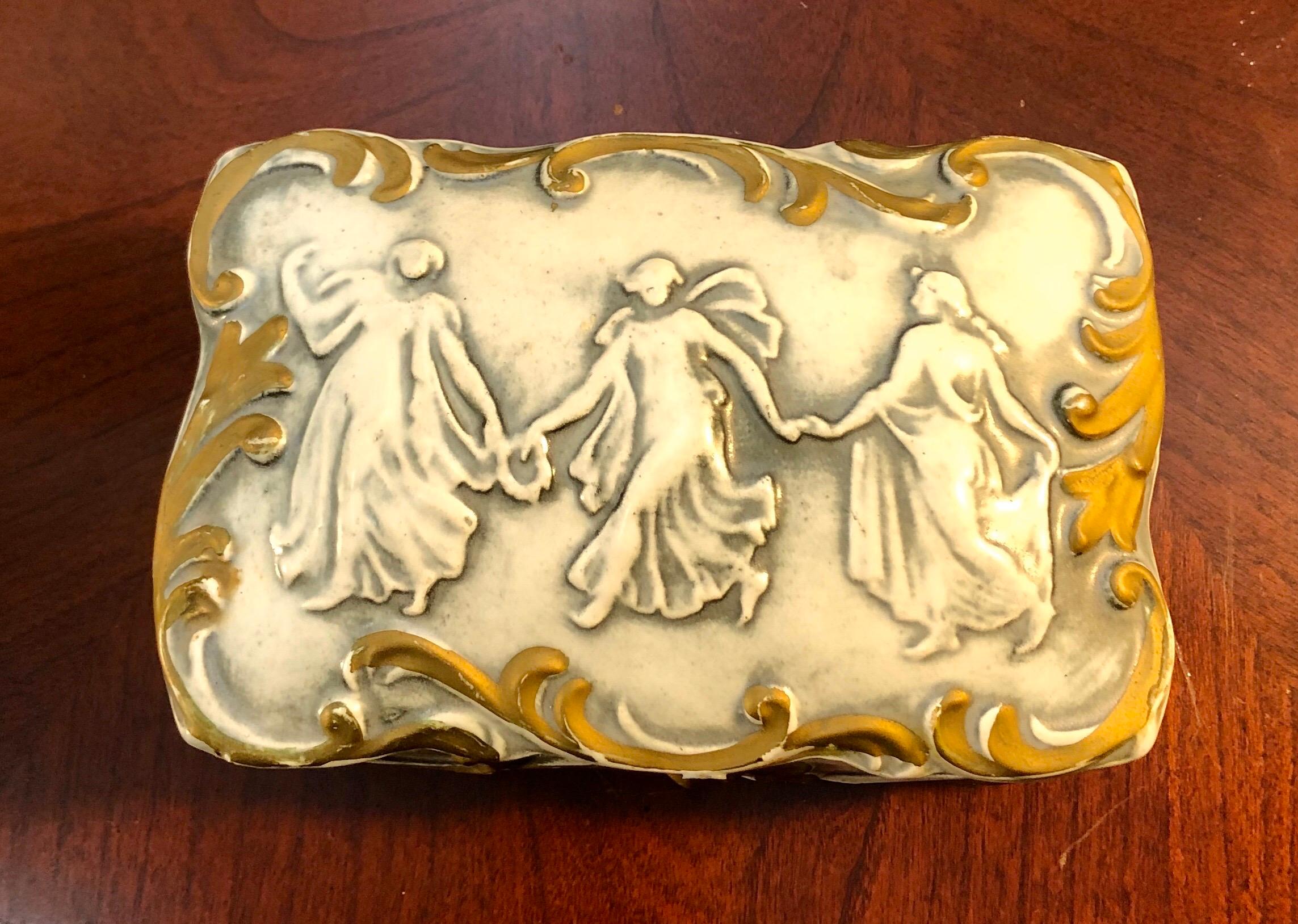 This antique French biscuit porcelain trinket box hails from the late 1800s and is in excellent condition. On the detached lid are the three graces, ethereal and lovely. The box open to reveal two trays, perfect to use for rings or other small