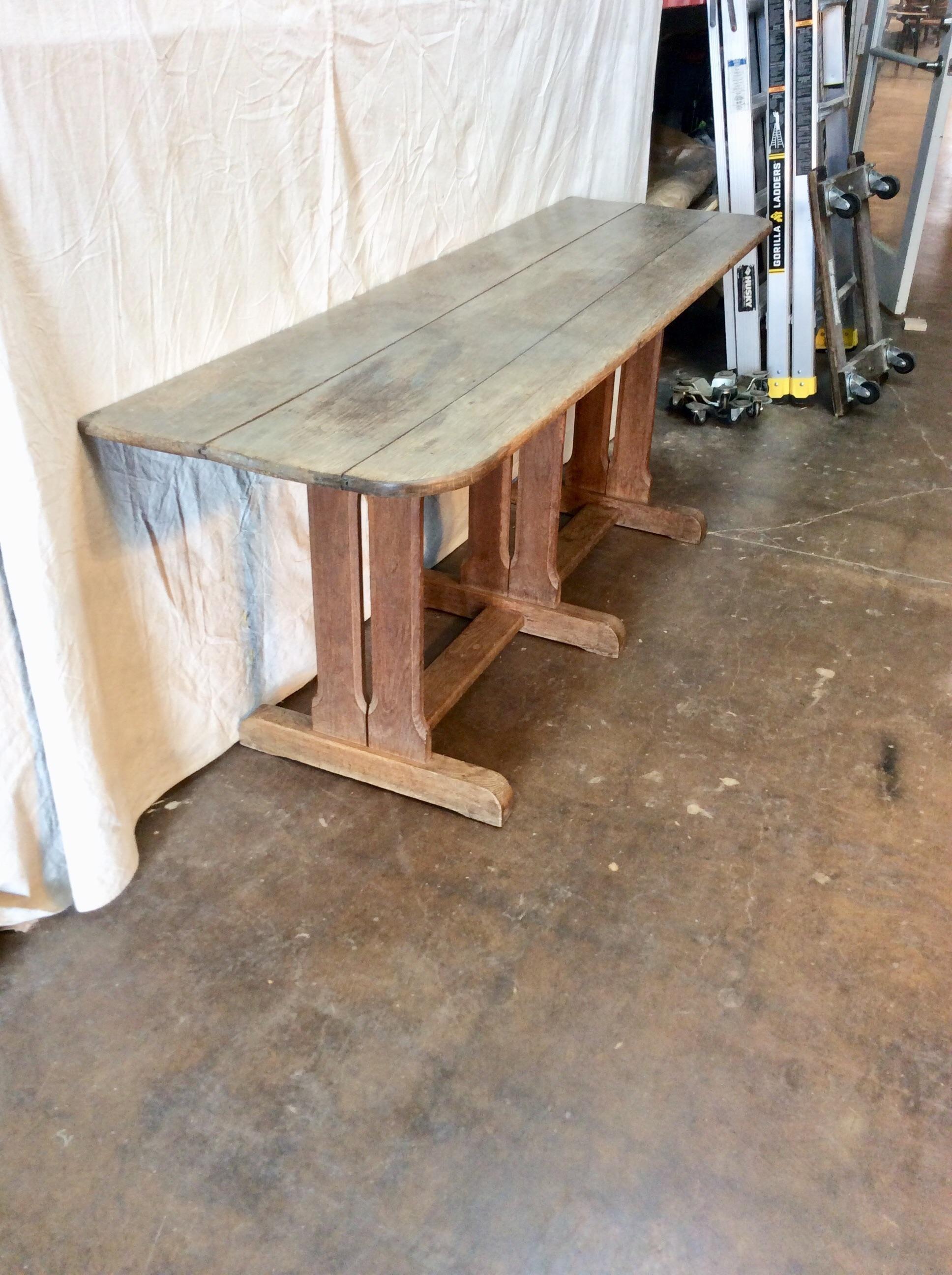 Found in France, this Late 1800s French Oak Trestle Console Table features clean simple lines and lots of charm. The hand carved top features rounded corners on the front and straight edges on the back. The rectangular top is supported by iron
