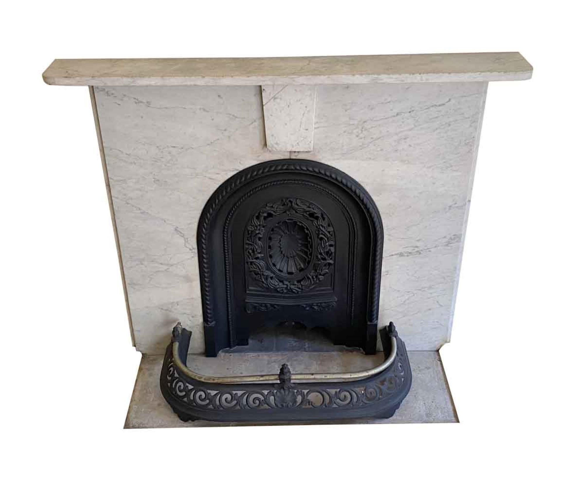 This very simple and petite 19th century Victorian Carrara marble mantel is from a NYC townhouse. It comes with the complete original cast iron summer cover surround and insert. The original keystone was cracked and mended as seen in pictures. This
