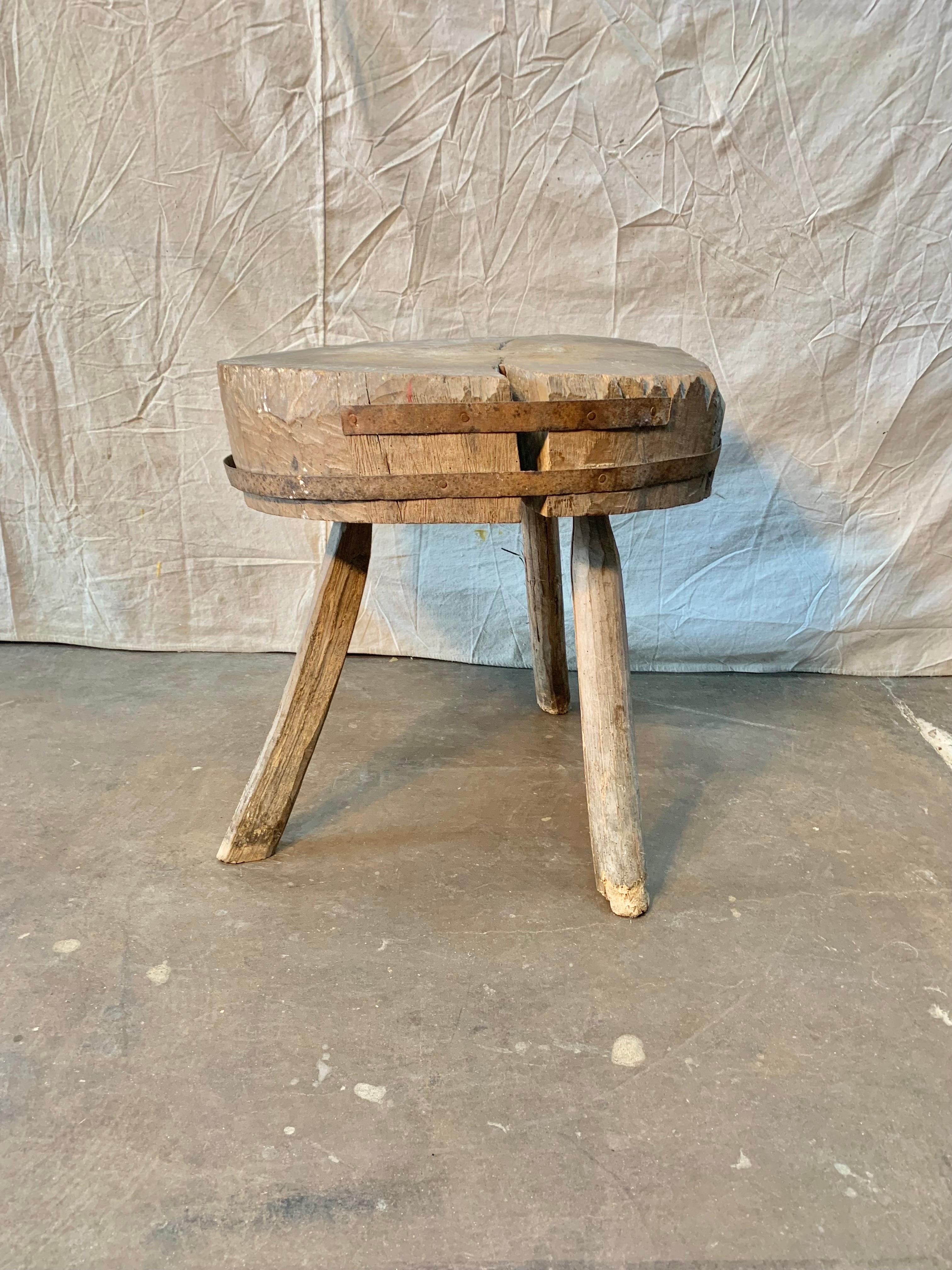 Found in the Provence region of France, this rustic French Butcher Table was once used in an outdoor market or on a farm. Handmade from a single tree trunk and secured with iron straps, the butcher block stands on three legs. A unique accent table,