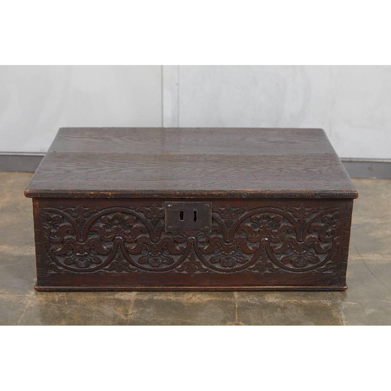 This carved oak bible box has a nice front panel with flora and fauna decorative elements. The piece has indications of its age including handmade nails and large old growth boards. The lock has worn away from the inside and the hinges were replaced