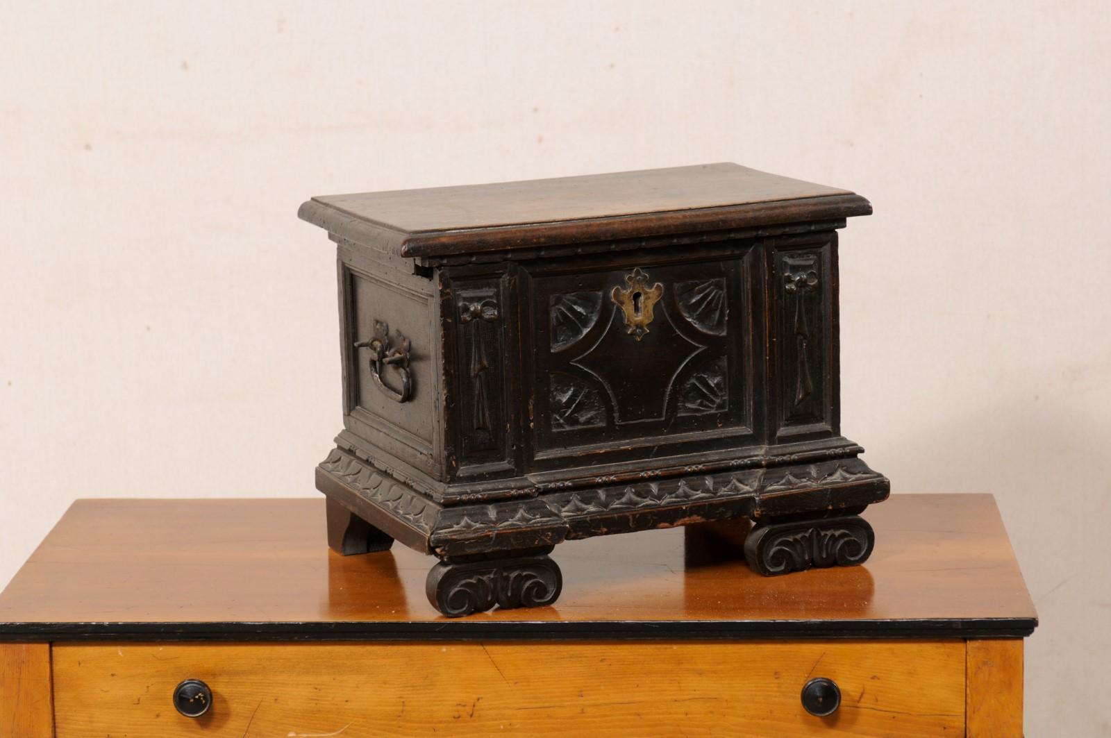 An English small-sized wooden box, circa 1770-1800. This antique box from England has been lovingly hand-carved with four quartered-wheels at each inner corner of the central panel, flanked within rectangular panels with hanging bows carved at their