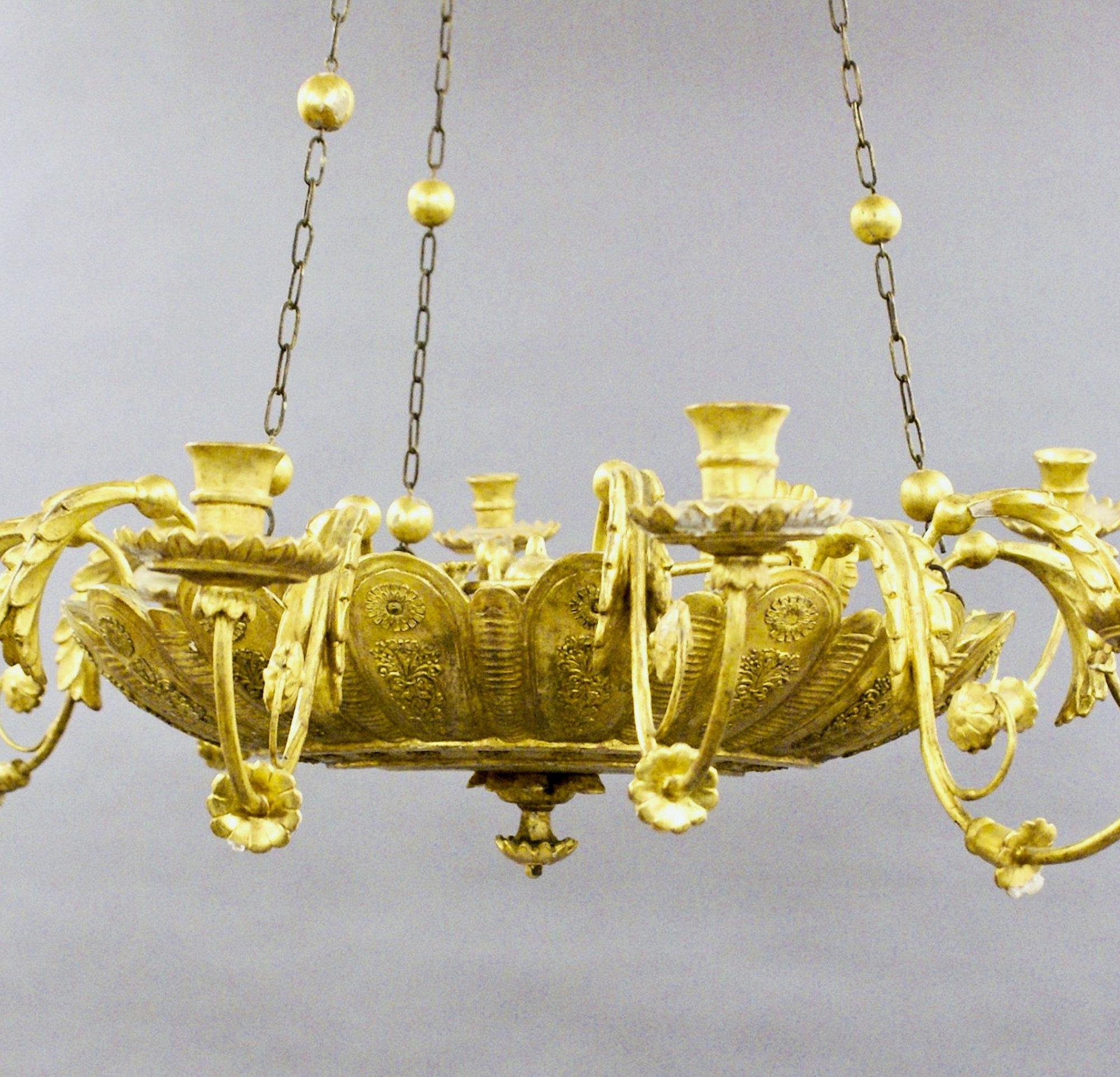 This stunning and beautifully crafted late 18th century giltwood chandelier features 10 shaped branches and scones, all ornately carved and embellished. The branches all connect to a central dish center with the original canopy and chains. The