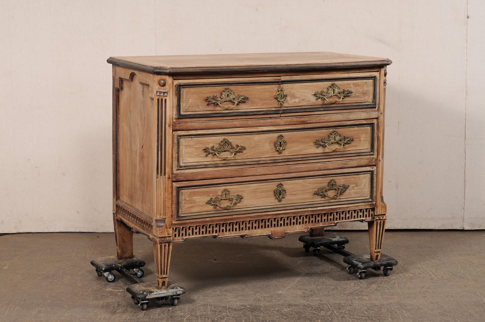 A French ornately carved wood chest of drawers from the turn of the 18th and 19th century. This antique commode from France has a rectangular-shaped top with canted front corners, over a case which houses a pair of half-sized drawers atop two
