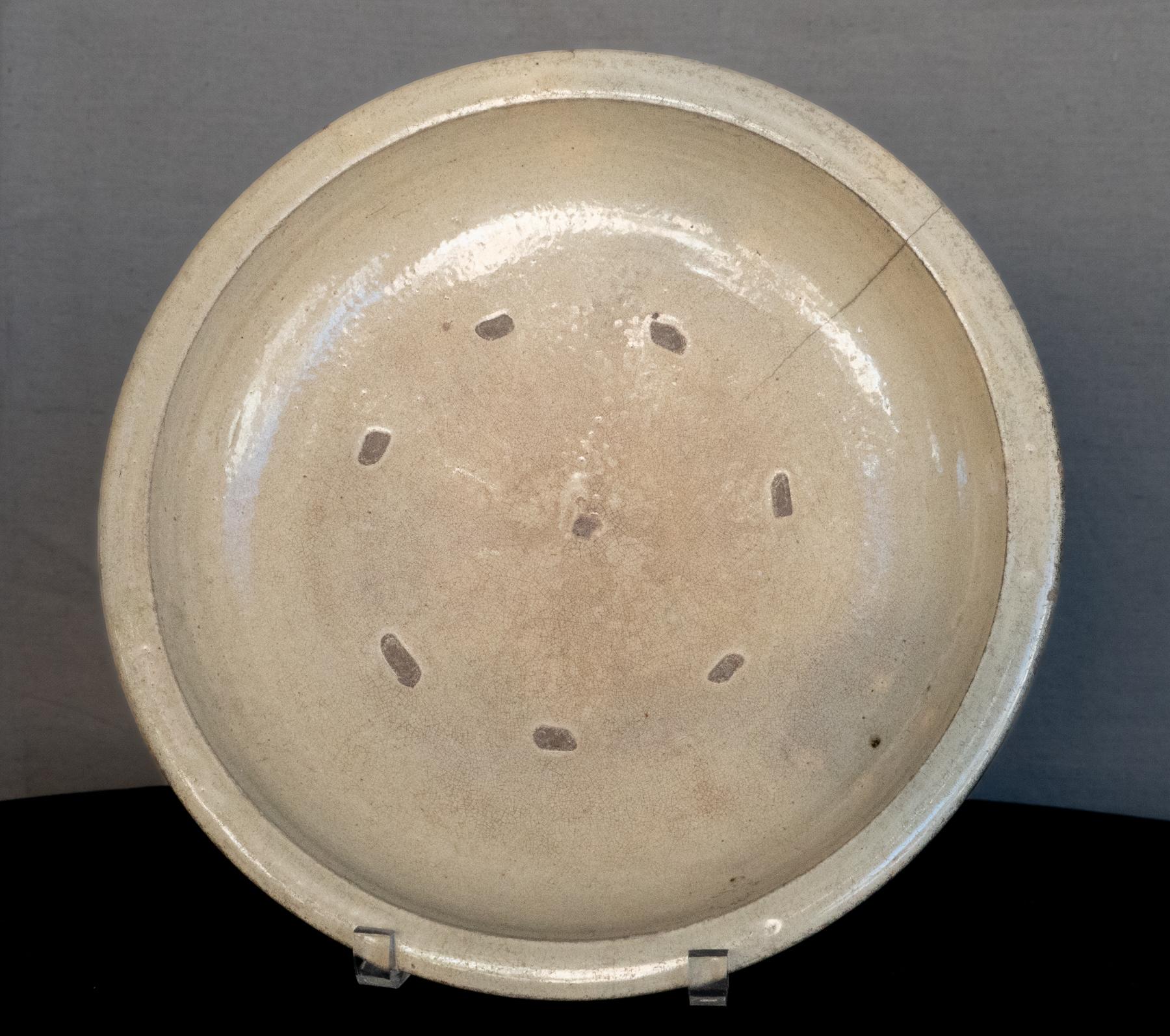 Late 18th century Japanese Celadon charger with good patina.
Good wear to the center of the plate and very fine crackle create a multi-layered hues to the glaze. Spur marks to the front of the plate in a radial pattern and an age crack. The ceramic