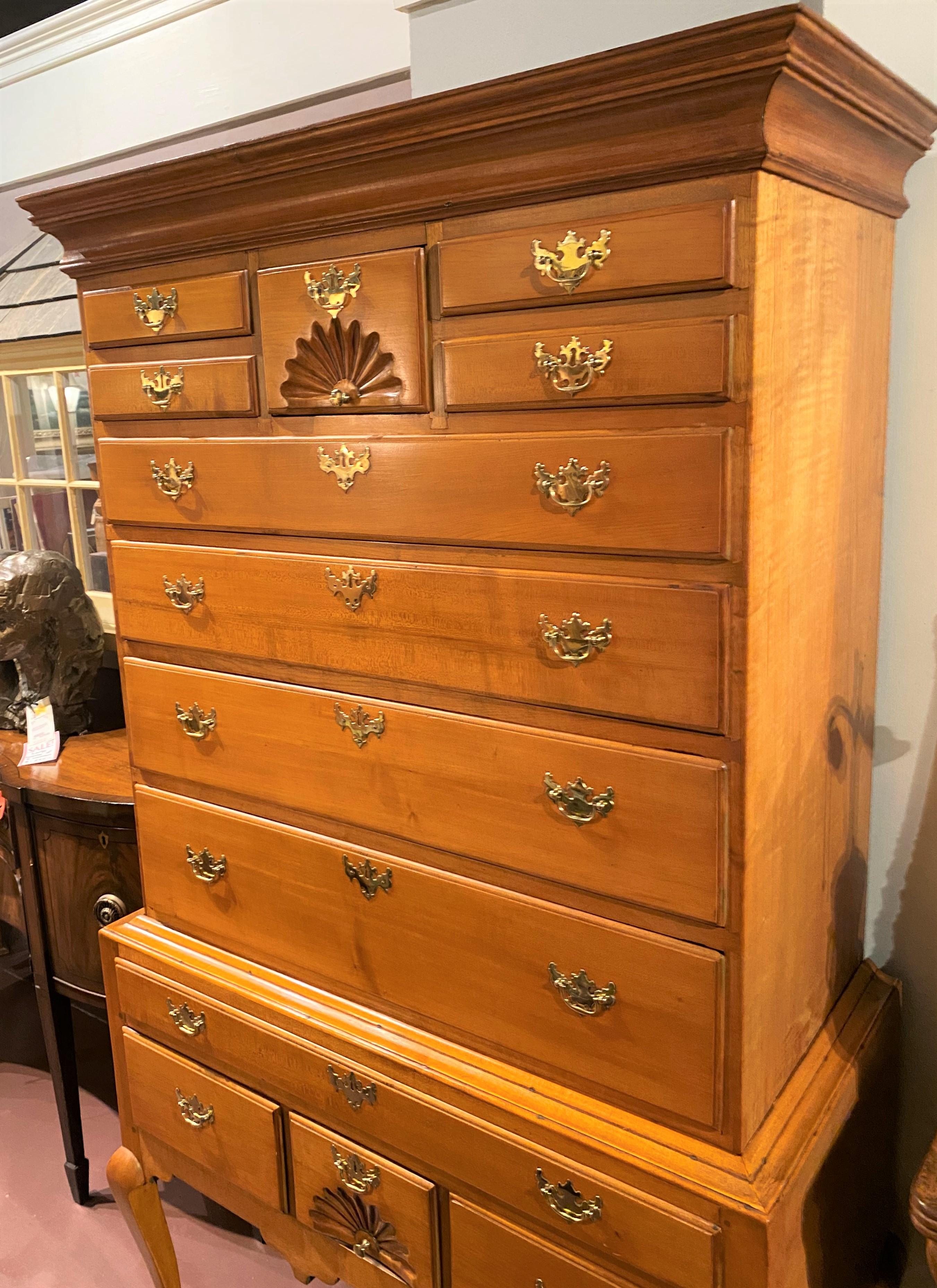 A nice example of a late 18th century New England maple highboy or high chest, its upper case with a molded cornice surmounting a central fan carved drawer flanked by four fitted small drawers over four graduated long drawers, over a lower case with