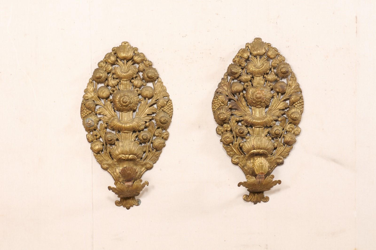 A French pair of brass repoussé single-light wall sconces from the late 18th century. This antique pair of wall decorations from France, Circa 1780-1800, have been created in brass with an ornate pierced repoussage in floral motif. Each sconce has a