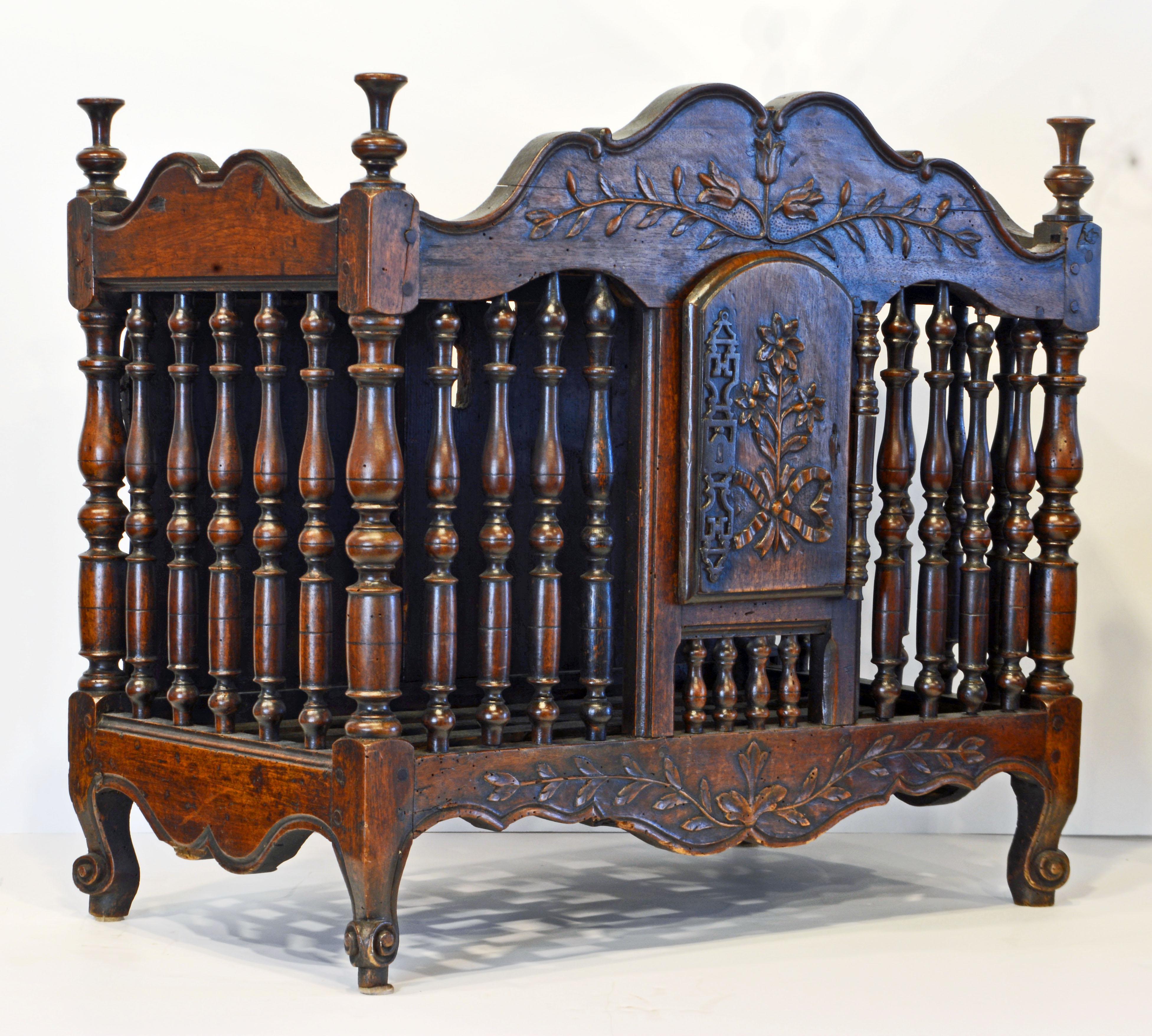 This fine late 18th century French Provincial walnut panetiere features a top with turned finials accenting the corners above shaped friezes on three sides adorned by carved flowers and leaves. The front and sides are are made with turned spindles