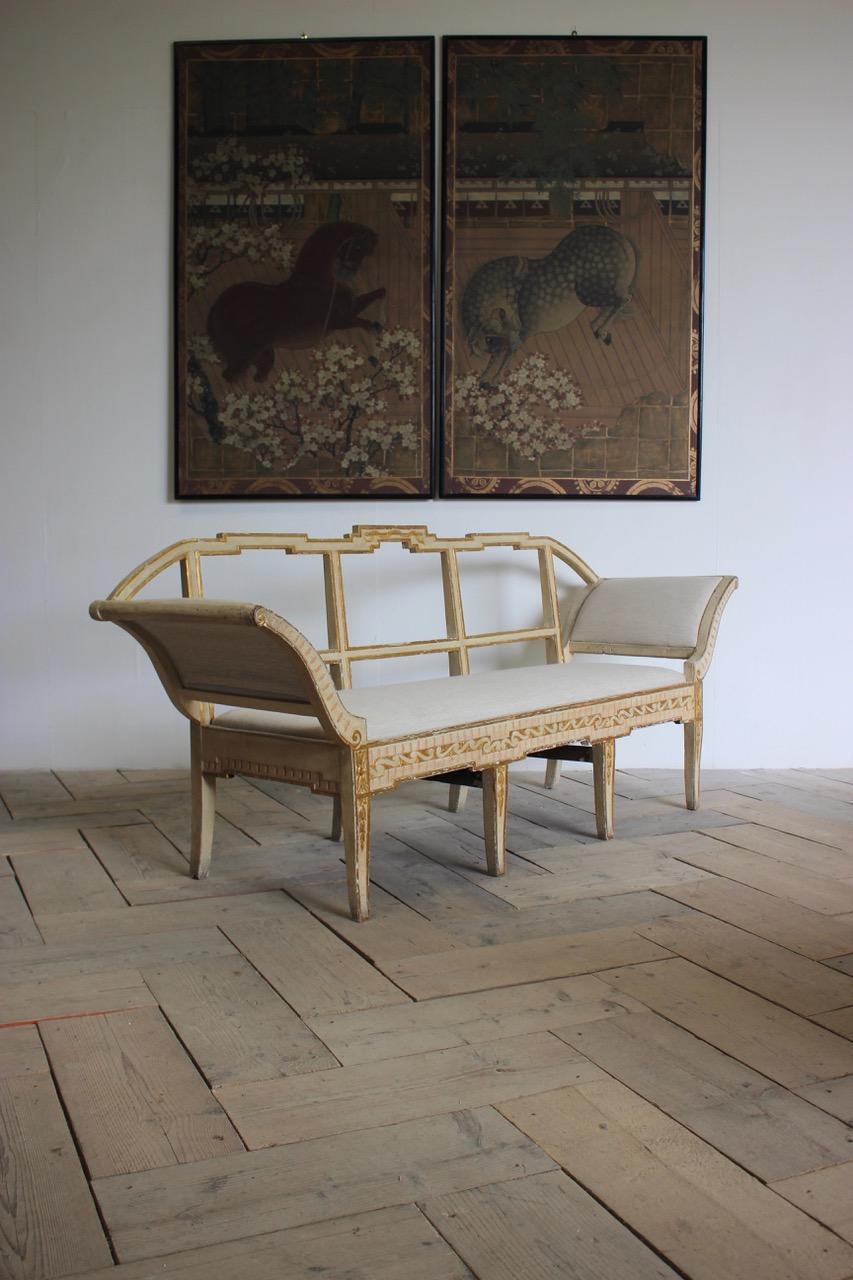 A very elegant late 18th century gilded and painted Italian sofa or bench in the classical taste upholstered in a neutral linen.

Measurements: 45cm high (floor to seat) 
Italy.
 